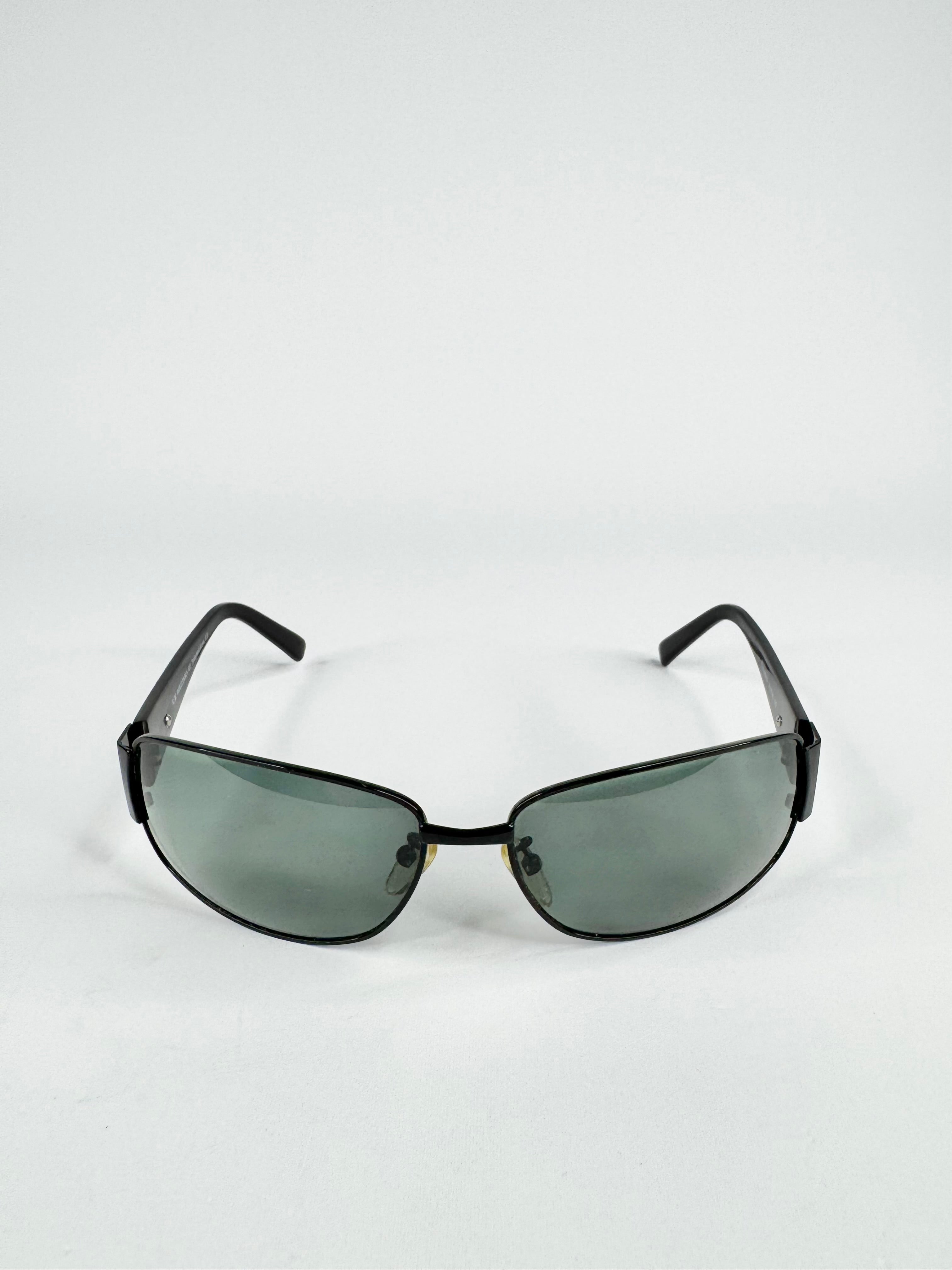 Sunglasses with black frame and green-tinted lenses on a white background