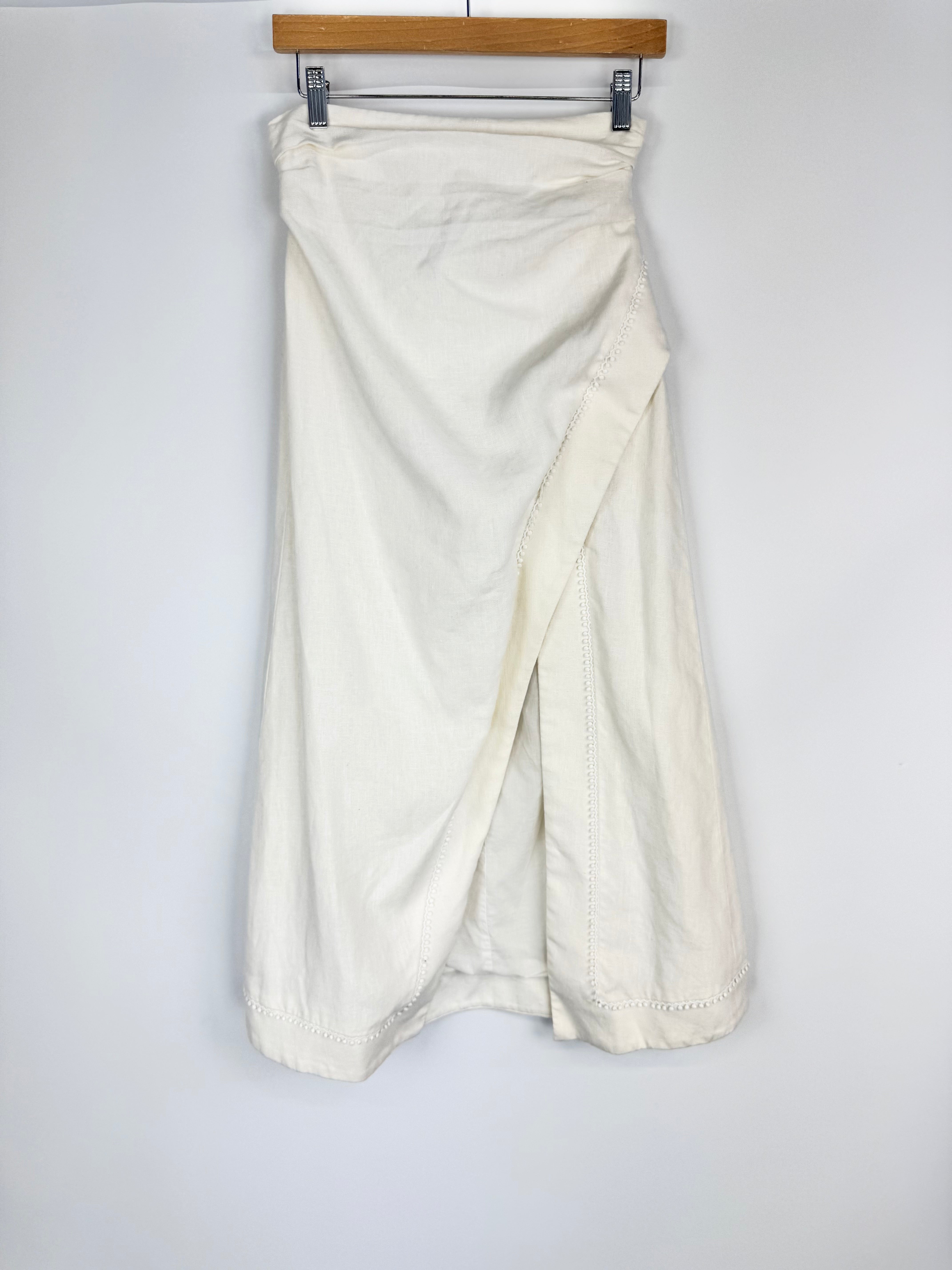 White drape skirt hanging on a wooden rod against a white background