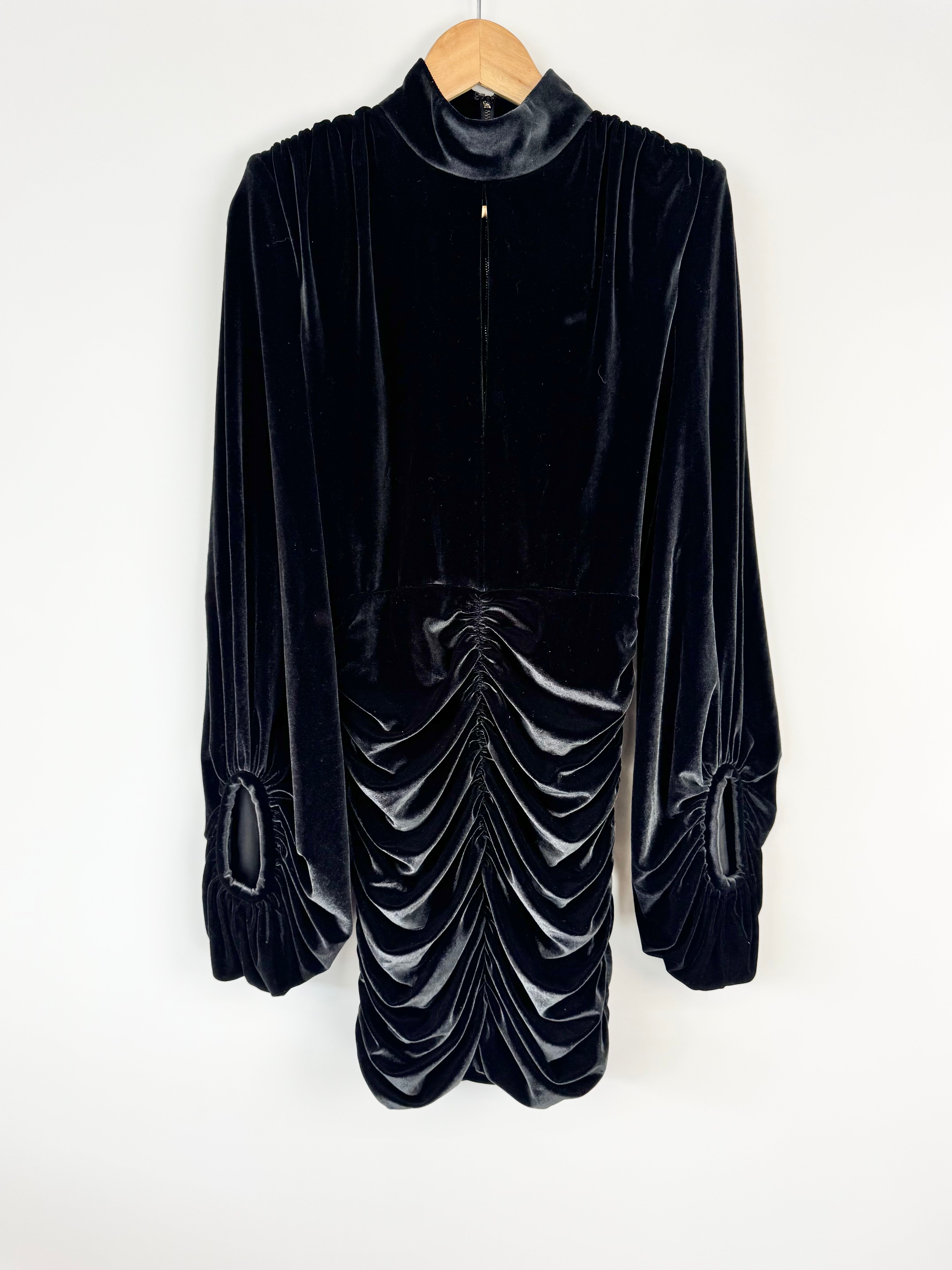 Black velvet dress on a hanger against a white background