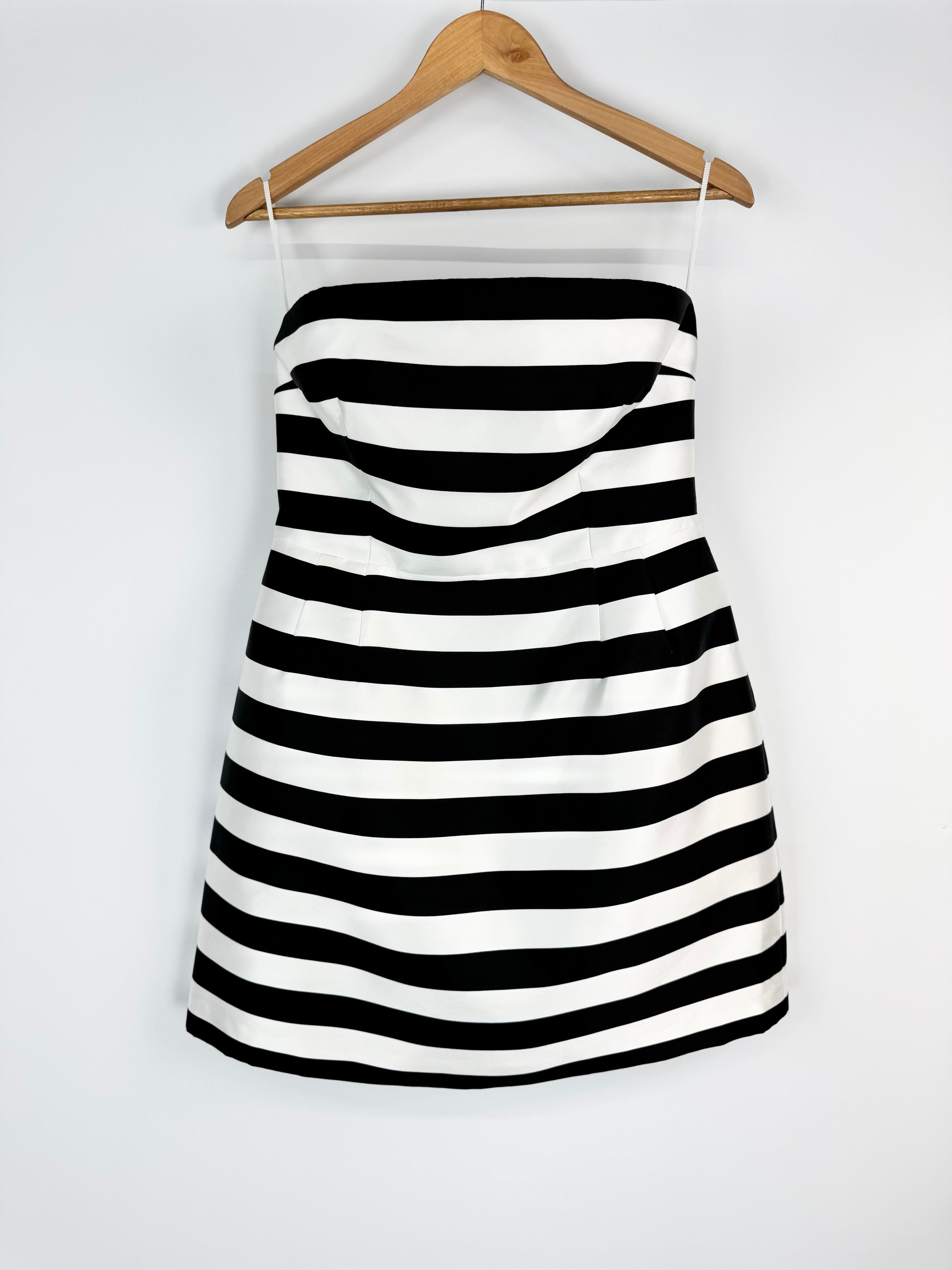 Black and white striped dress on a hanger against a white background