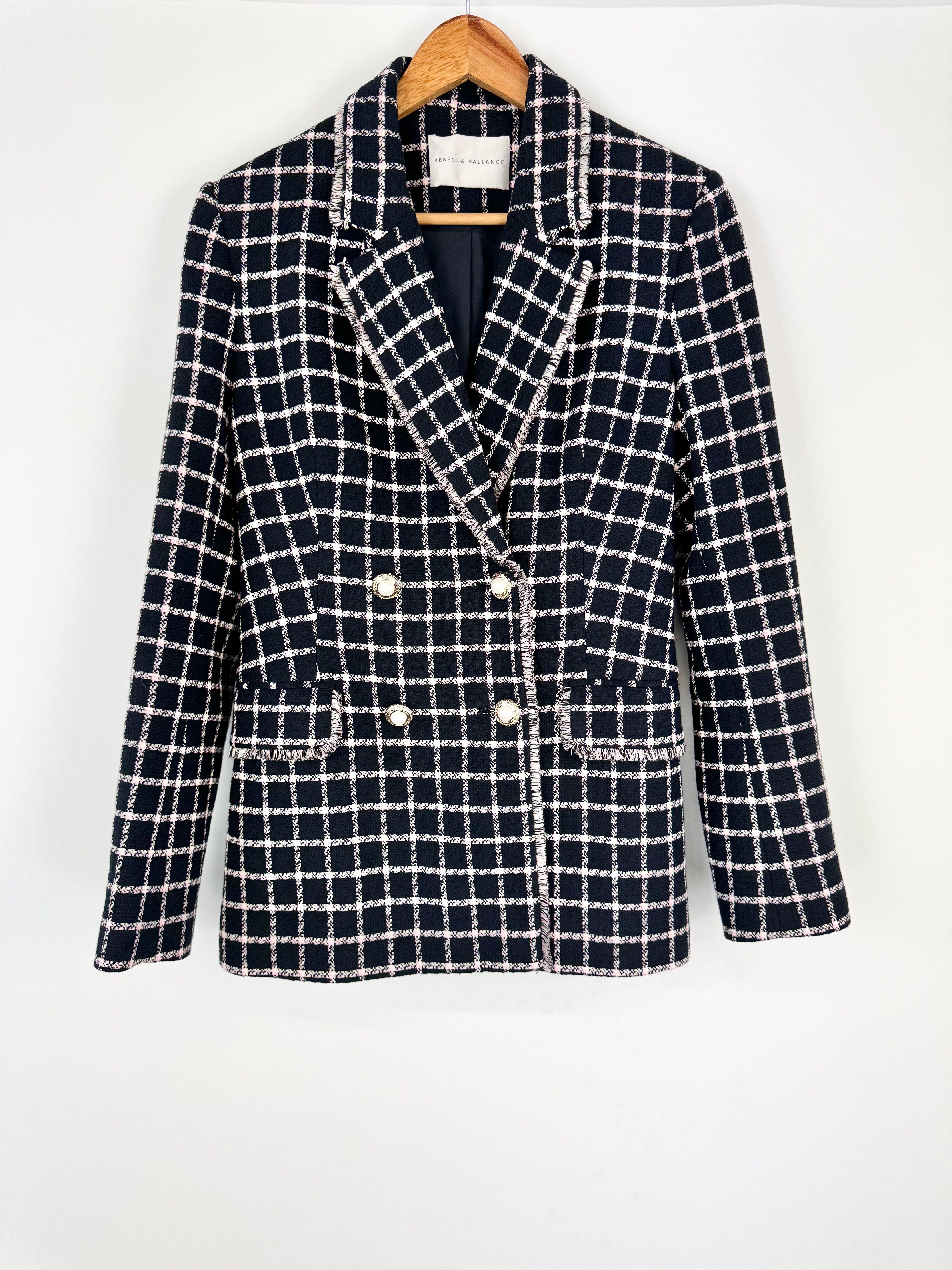 Black and white checkered blazer on a hanger against a white background