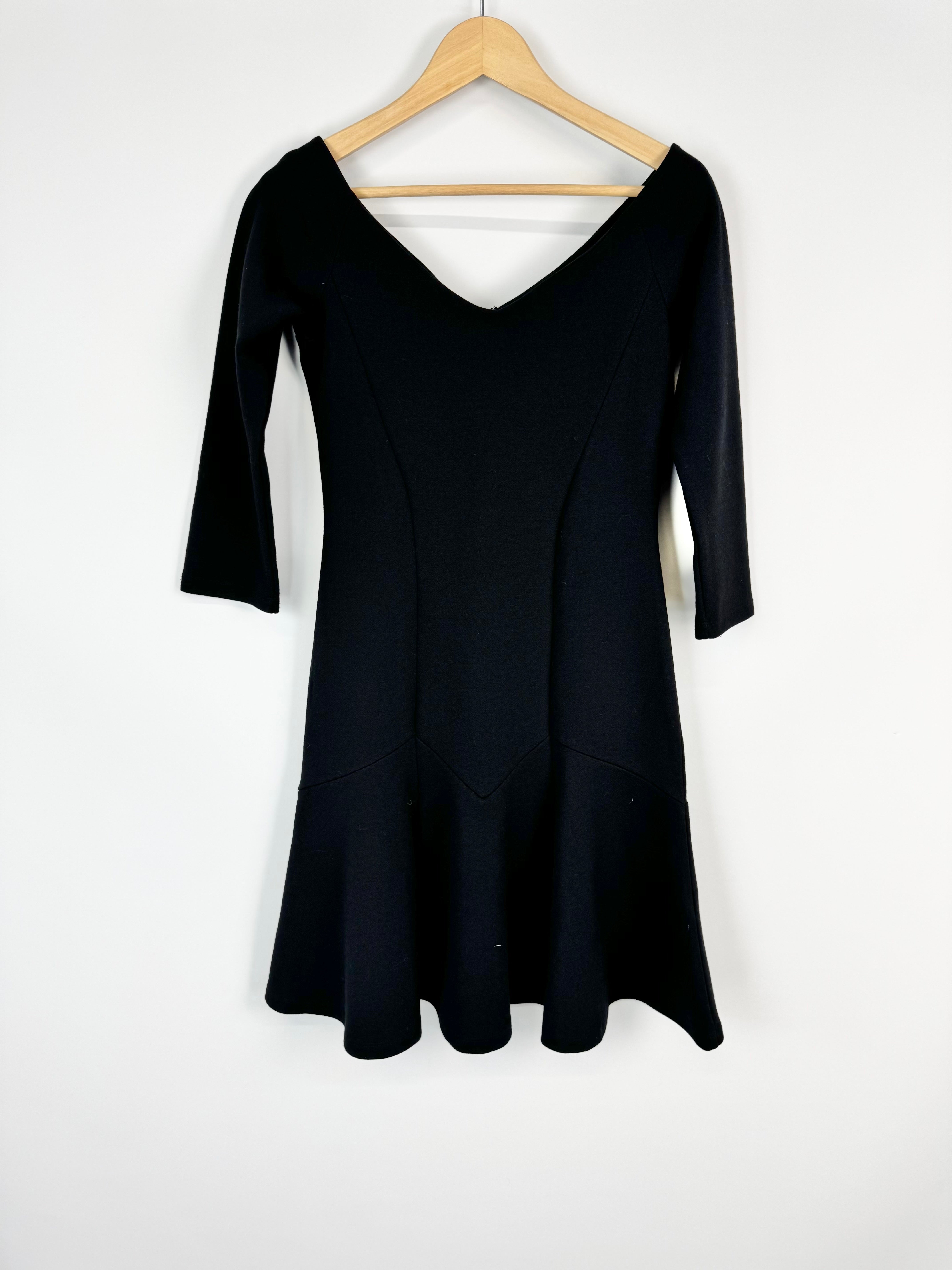 Black dress on a wooden hanger against a white background
