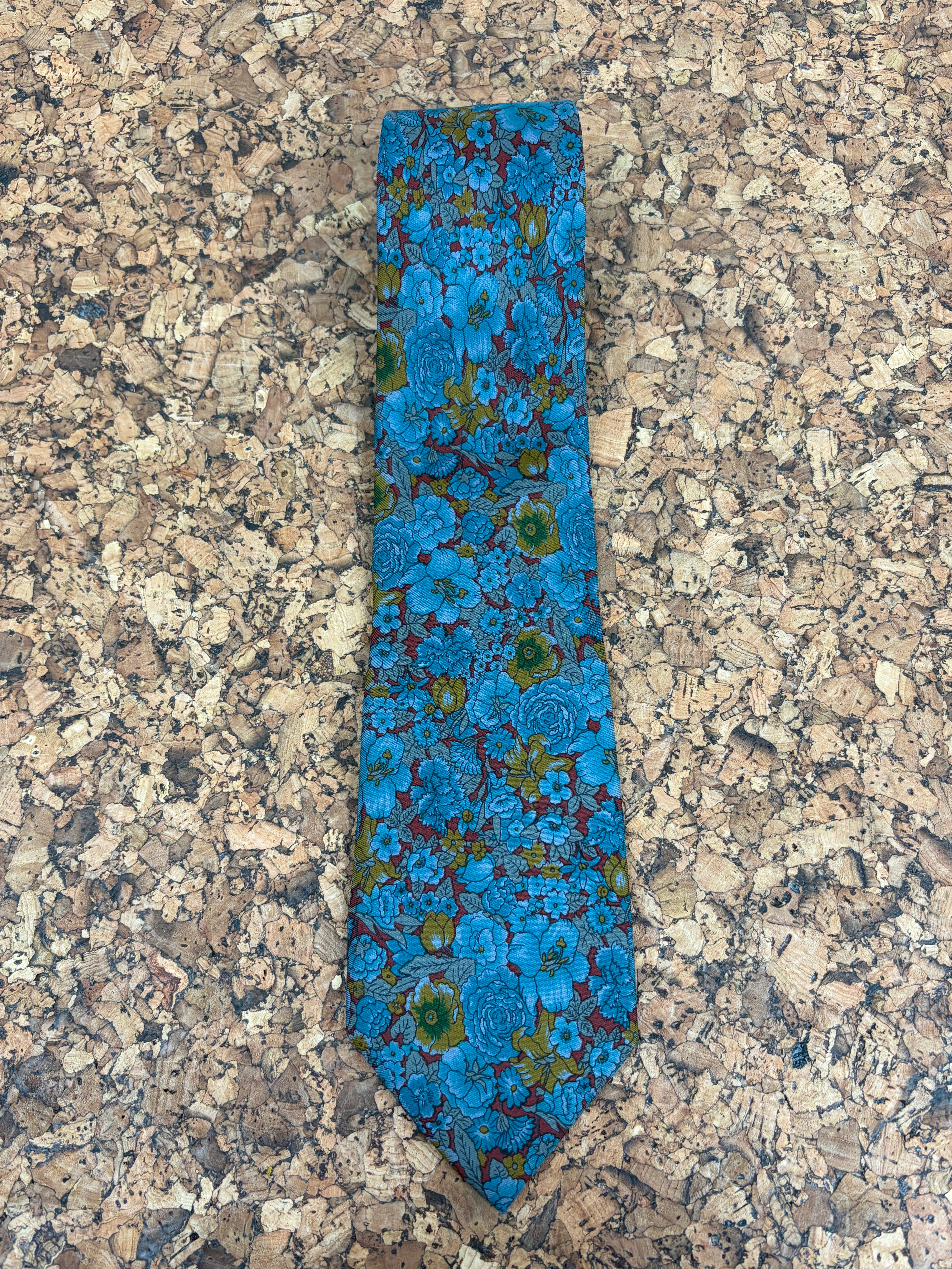 A blue patterned necktie with a floral design, laid flat on a speckled granite countertop.