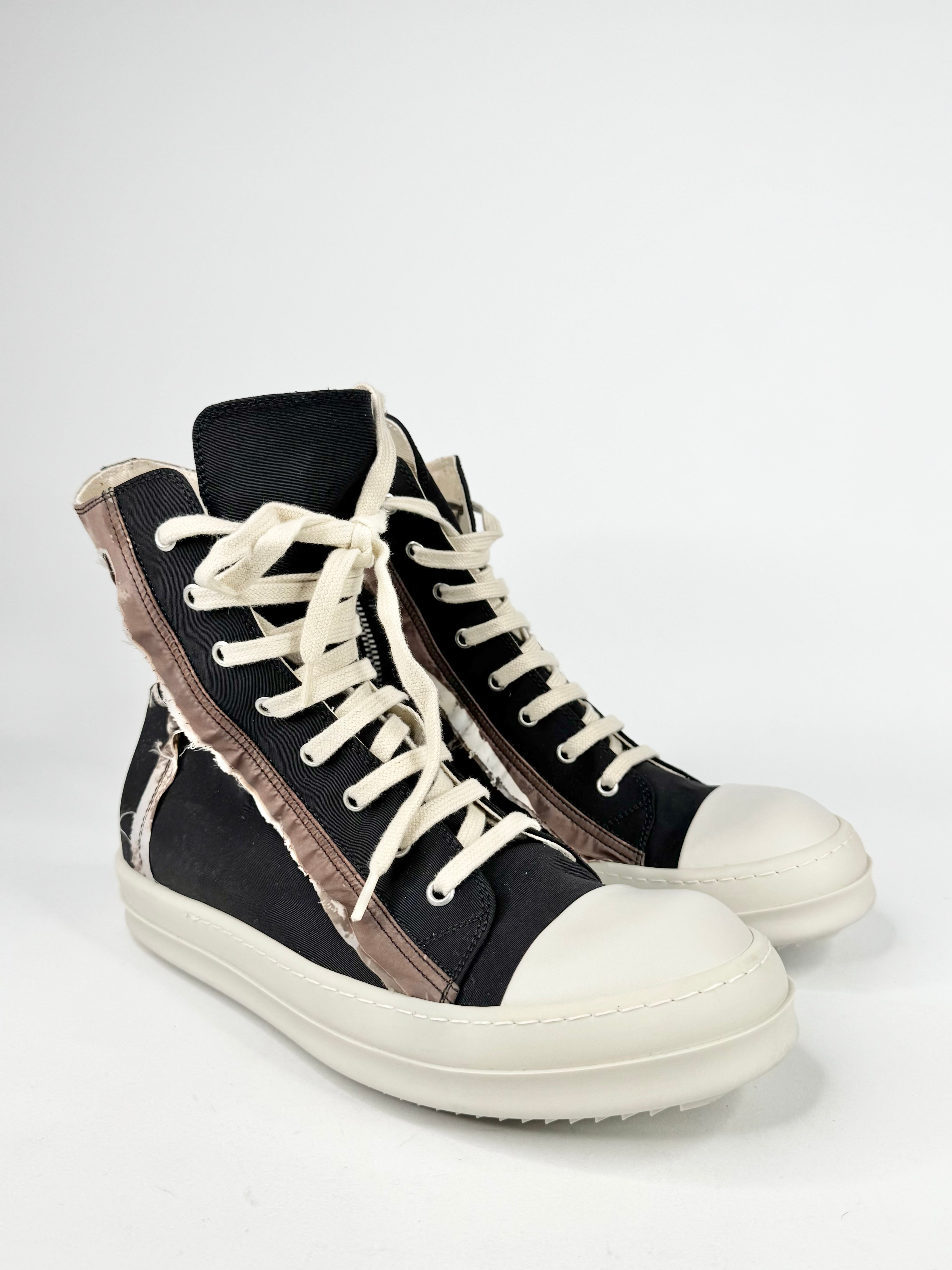 Black high-top sneakers with white soles on a light gray background