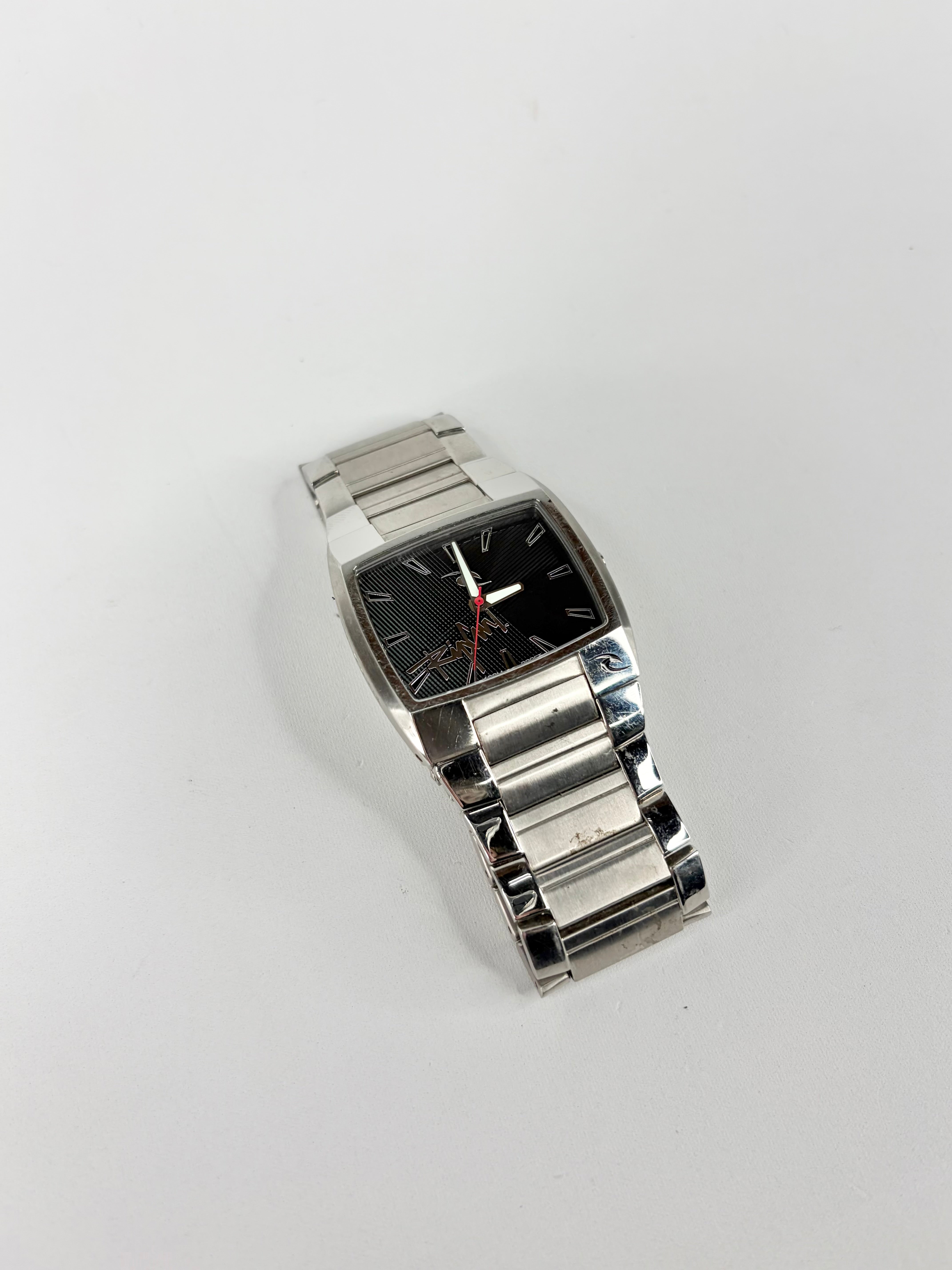 Silver wristwatch with a black face on a light gray background