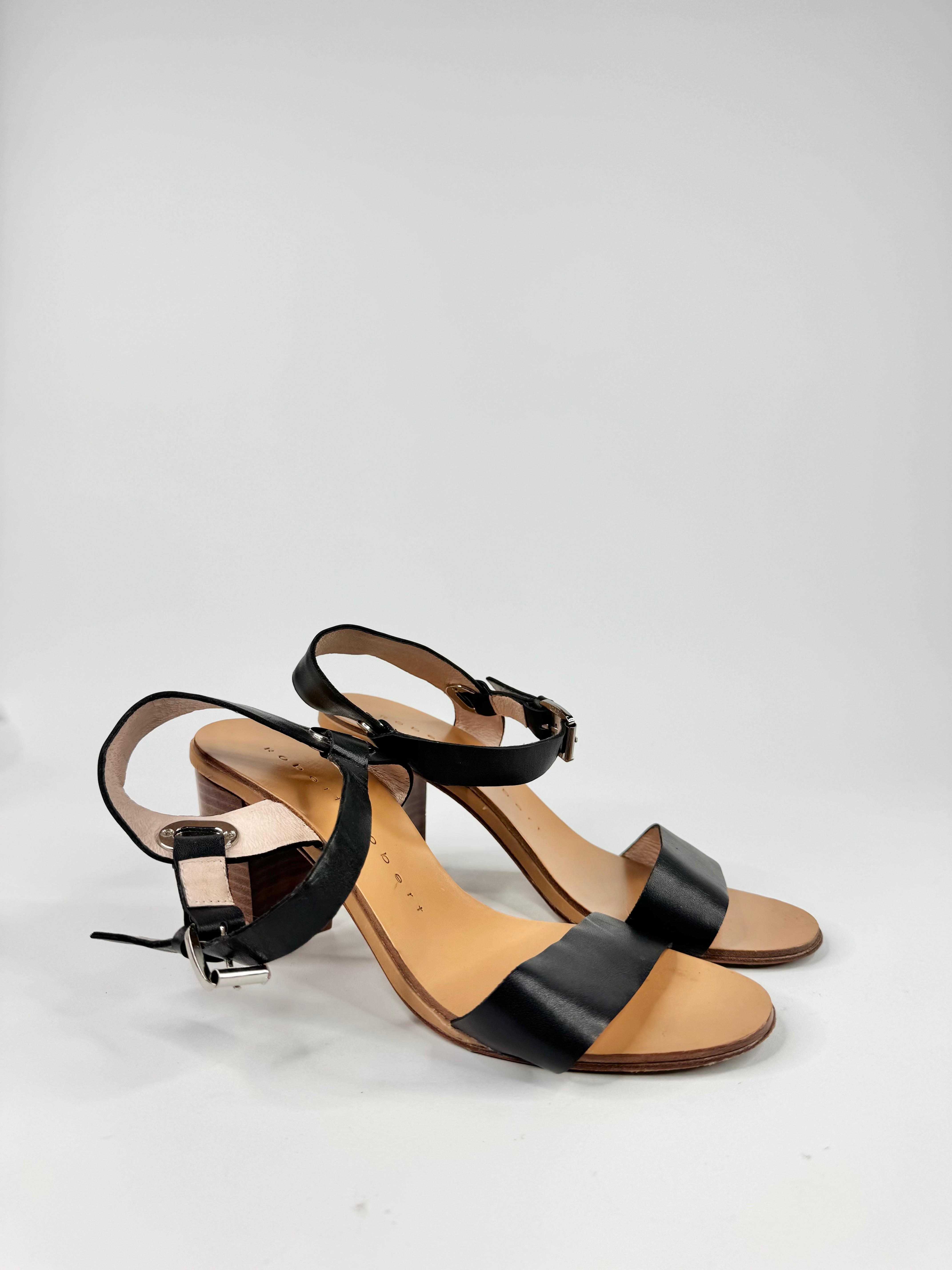 Pair of black and brown high-heeled sandals on a light gray background