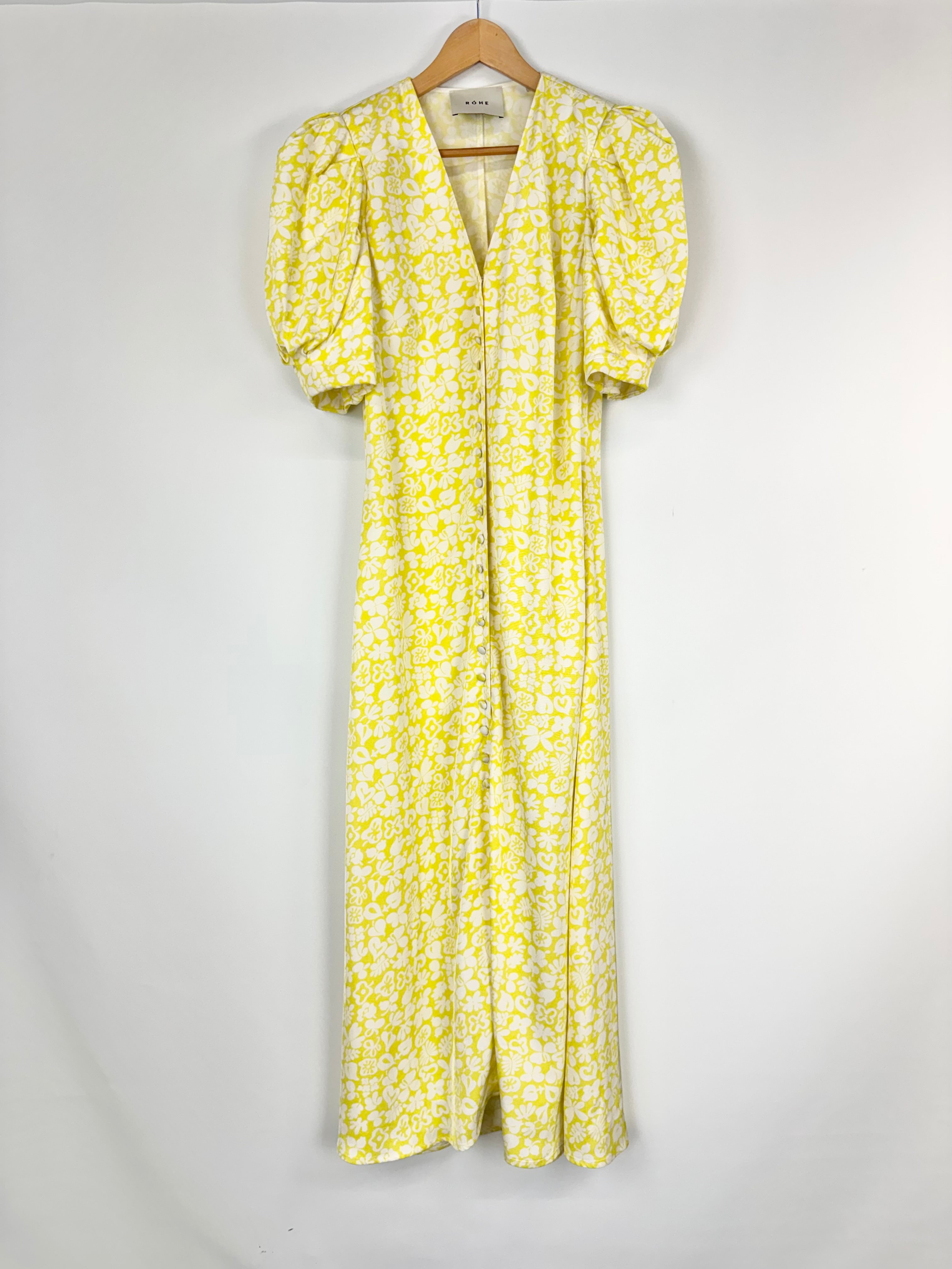 Yellow floral dress on a hanger against a white background