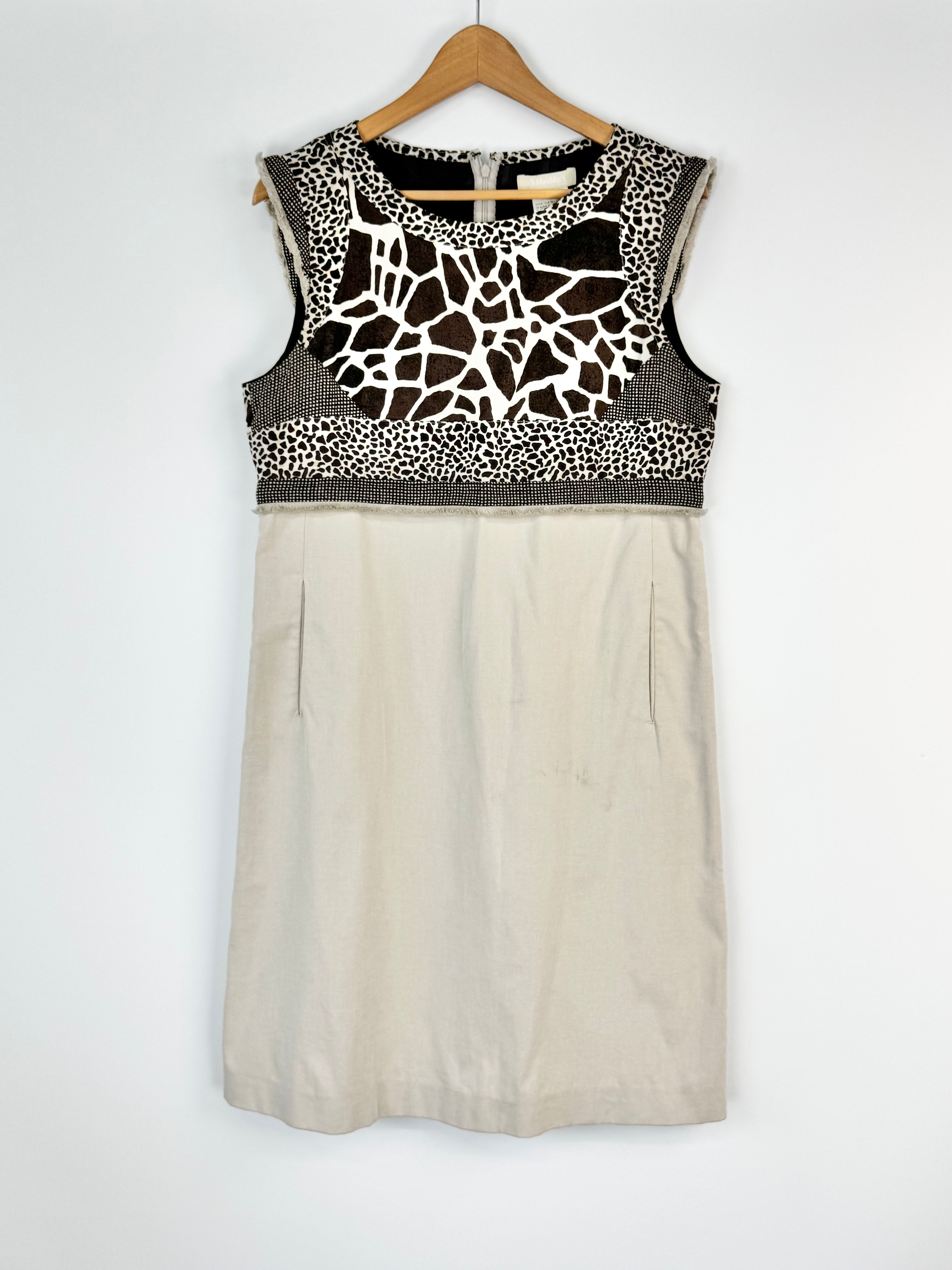 Beige sleeveless dress with black and white pattern on a hanger against a white background