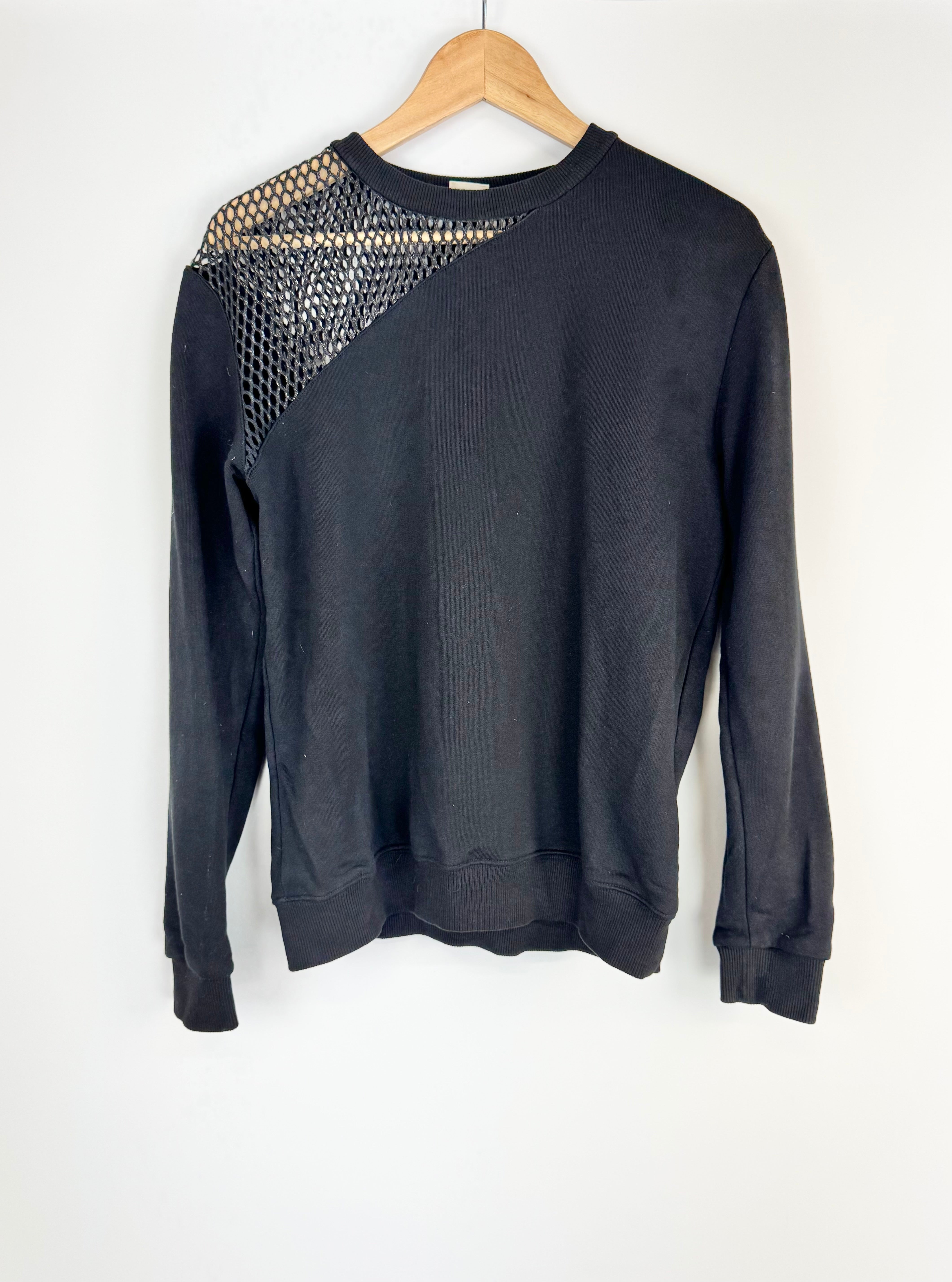 Black sweatshirt with mesh design on a wooden hanger against a white background