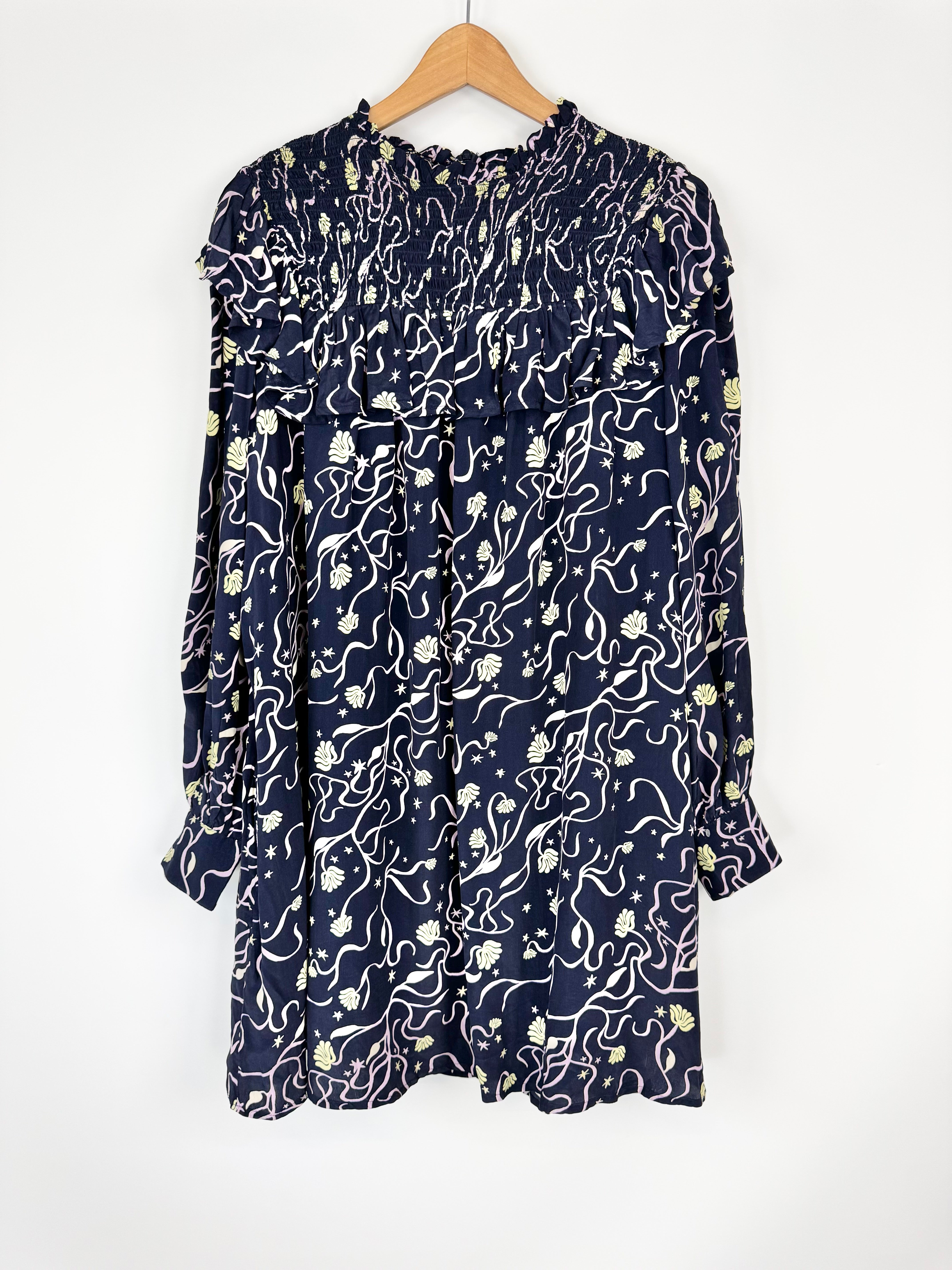 Navy dress with white floral pattern on a hanger against a white background