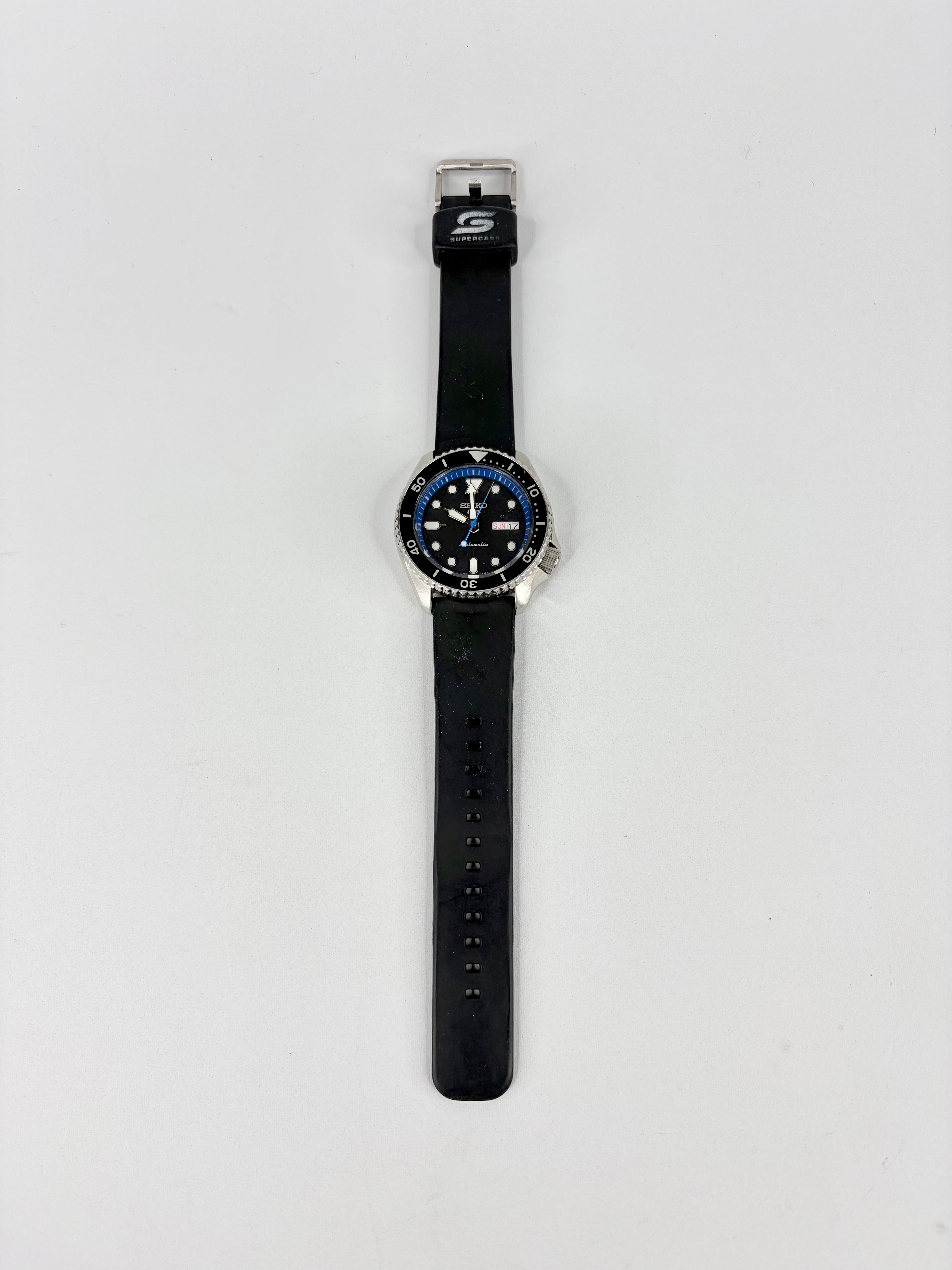 Black wristwatch with a blue face on a light gray background