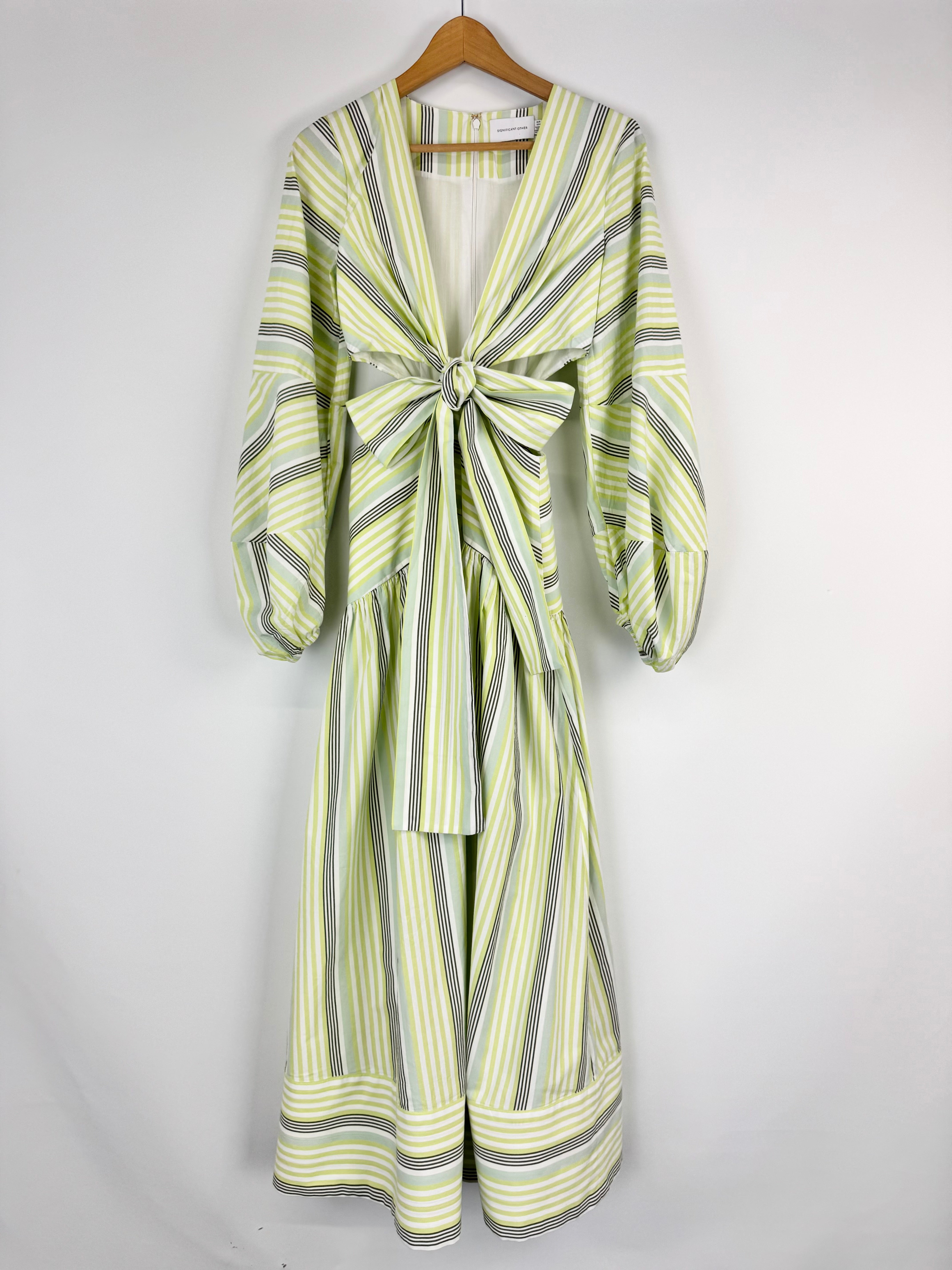 Striped dress with a bow detail on a hanger against a white background