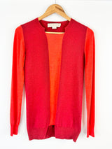 Red cardigan with orange lining on a wooden hanger against a white background