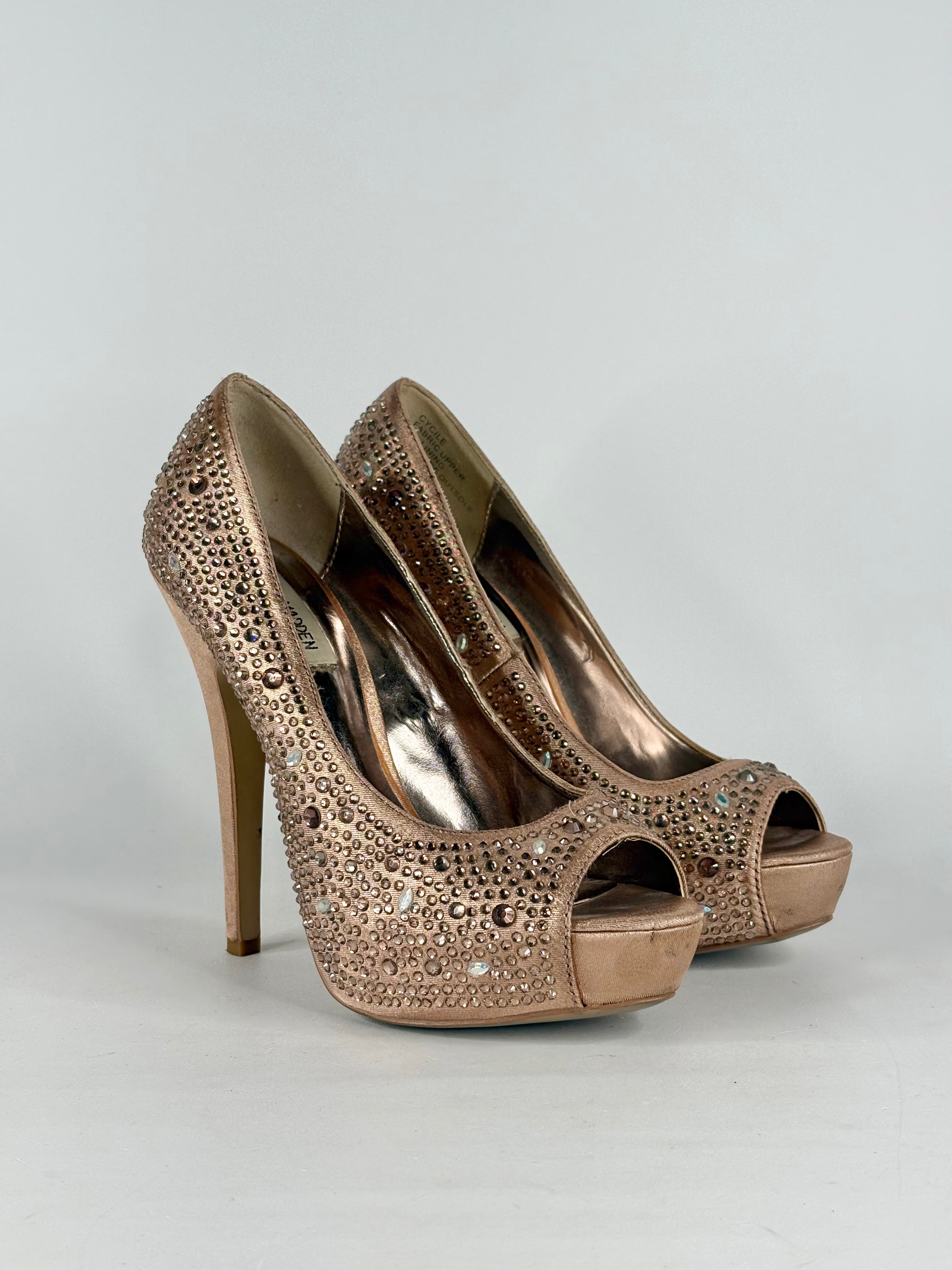Pair of bronze high-heeled shoes with crystal embellishments on a light gray background