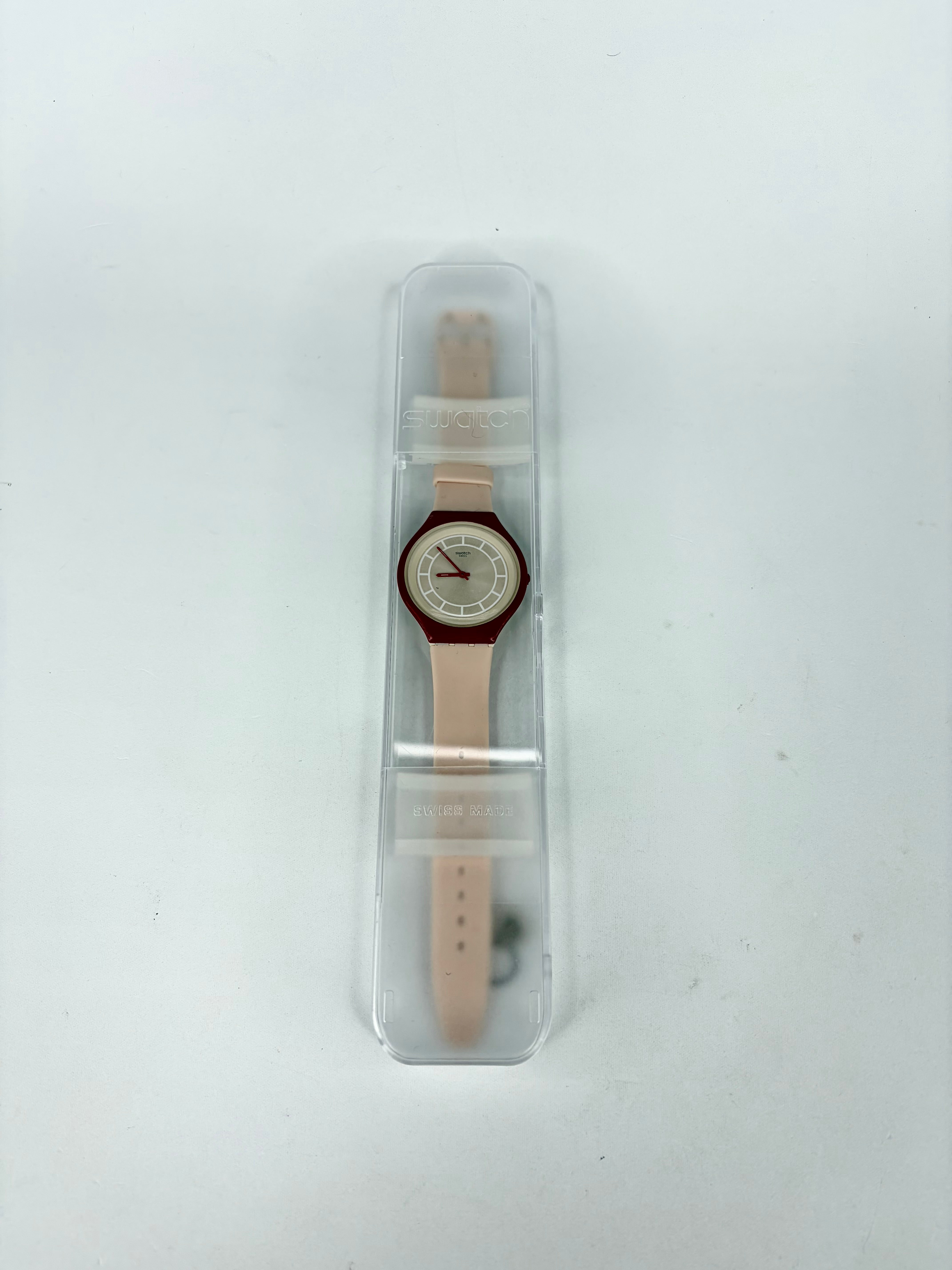 Watch with a brown strap in clear packaging on a white background