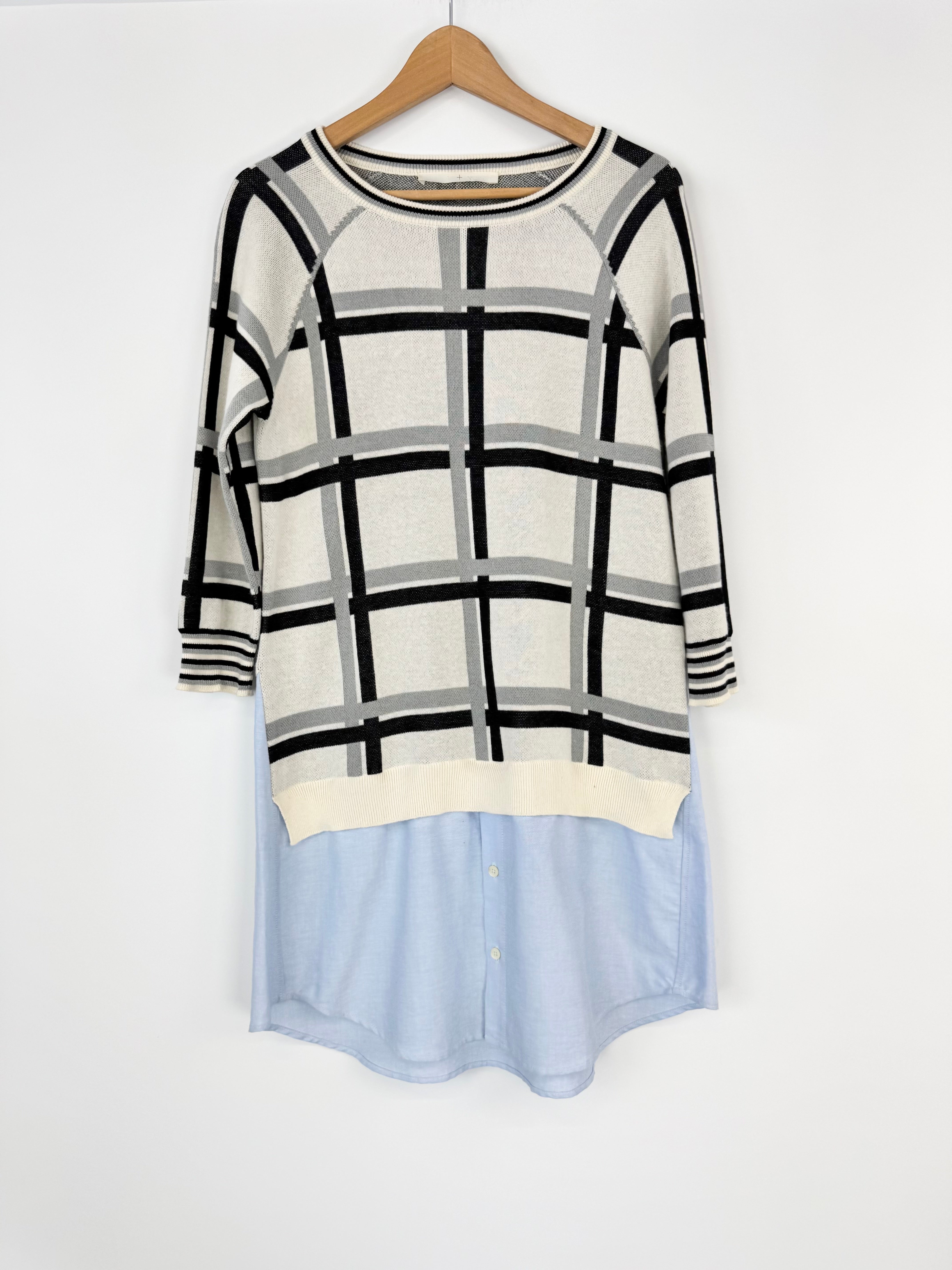 Plaid sweater with a light blue bottom section on a hanger against a white background