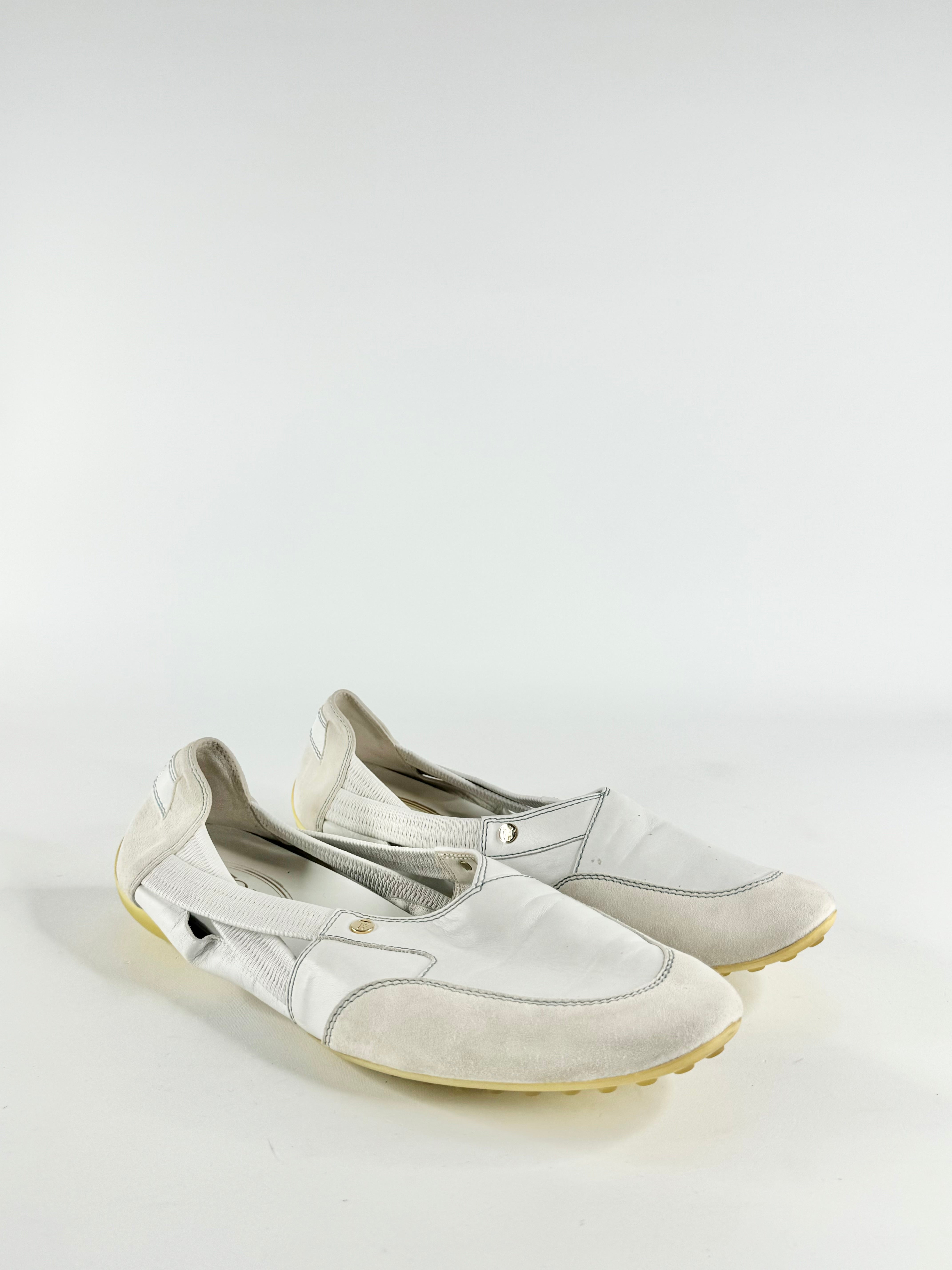 A pair of white leather and suede slip-on shoes with elasticated straps and a bumpy rubber sole, displayed against a white background.