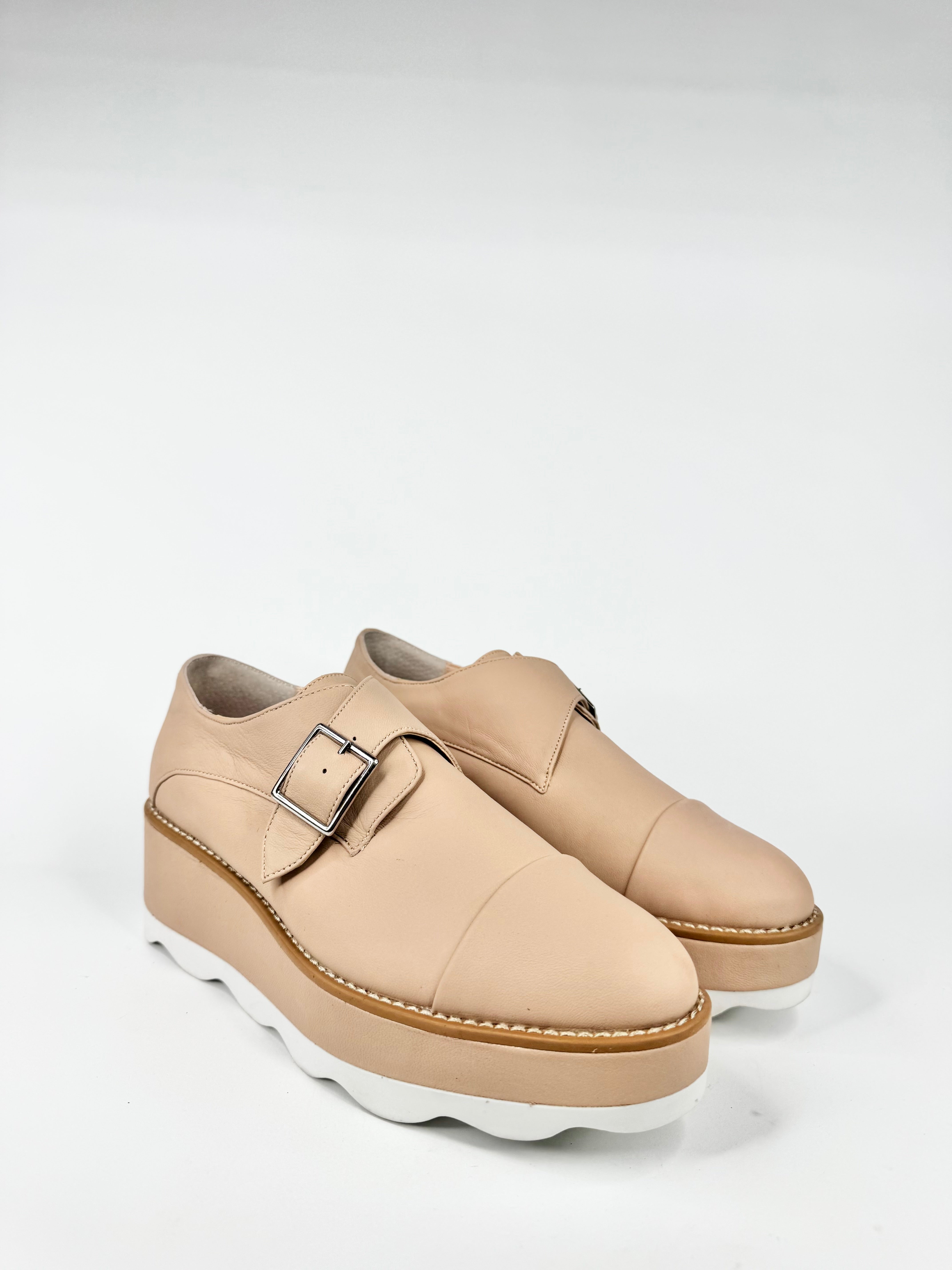 Beige platform shoes with a buckle on a light gray background
