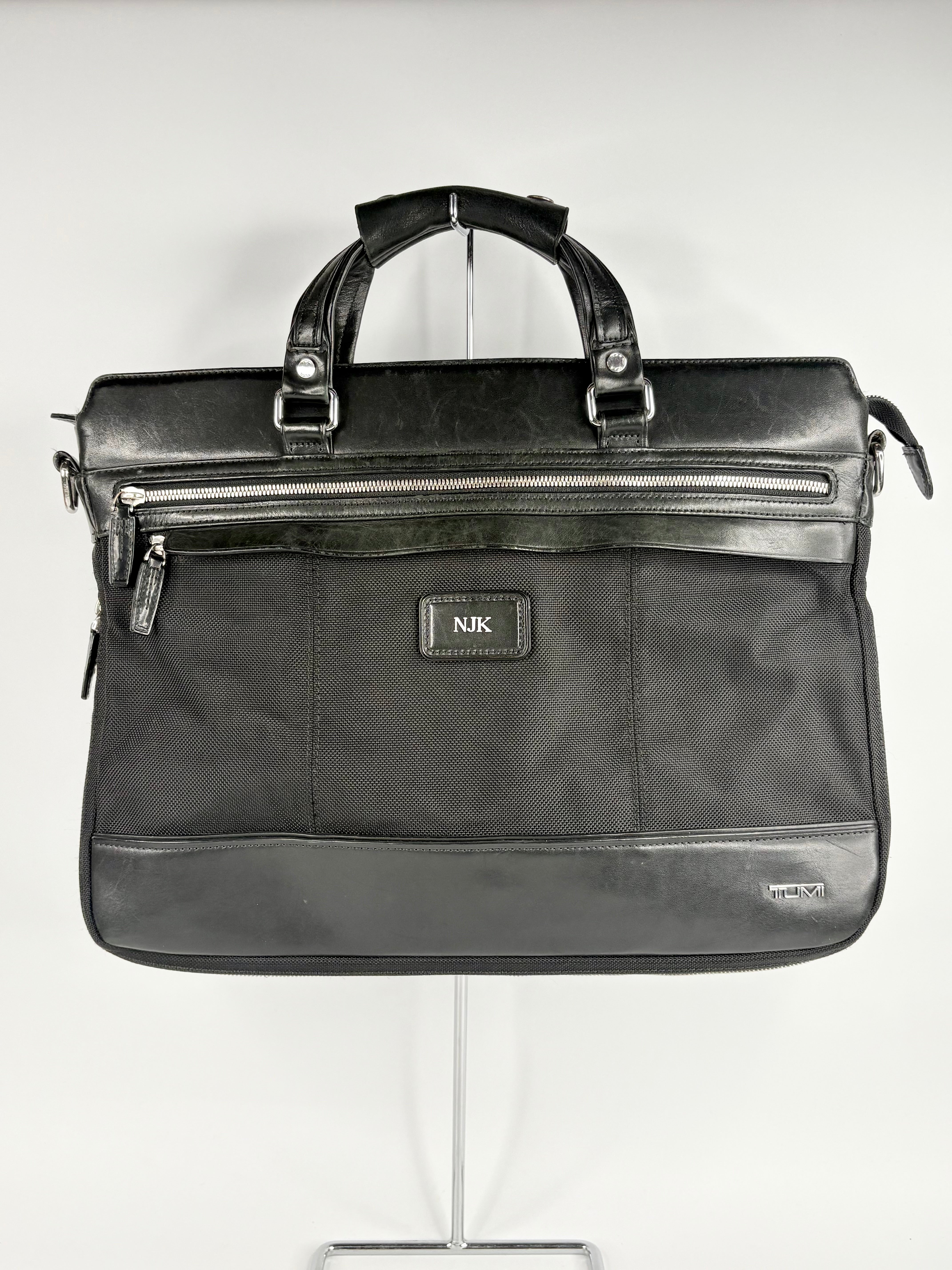 Black briefcase on a stand against a white background