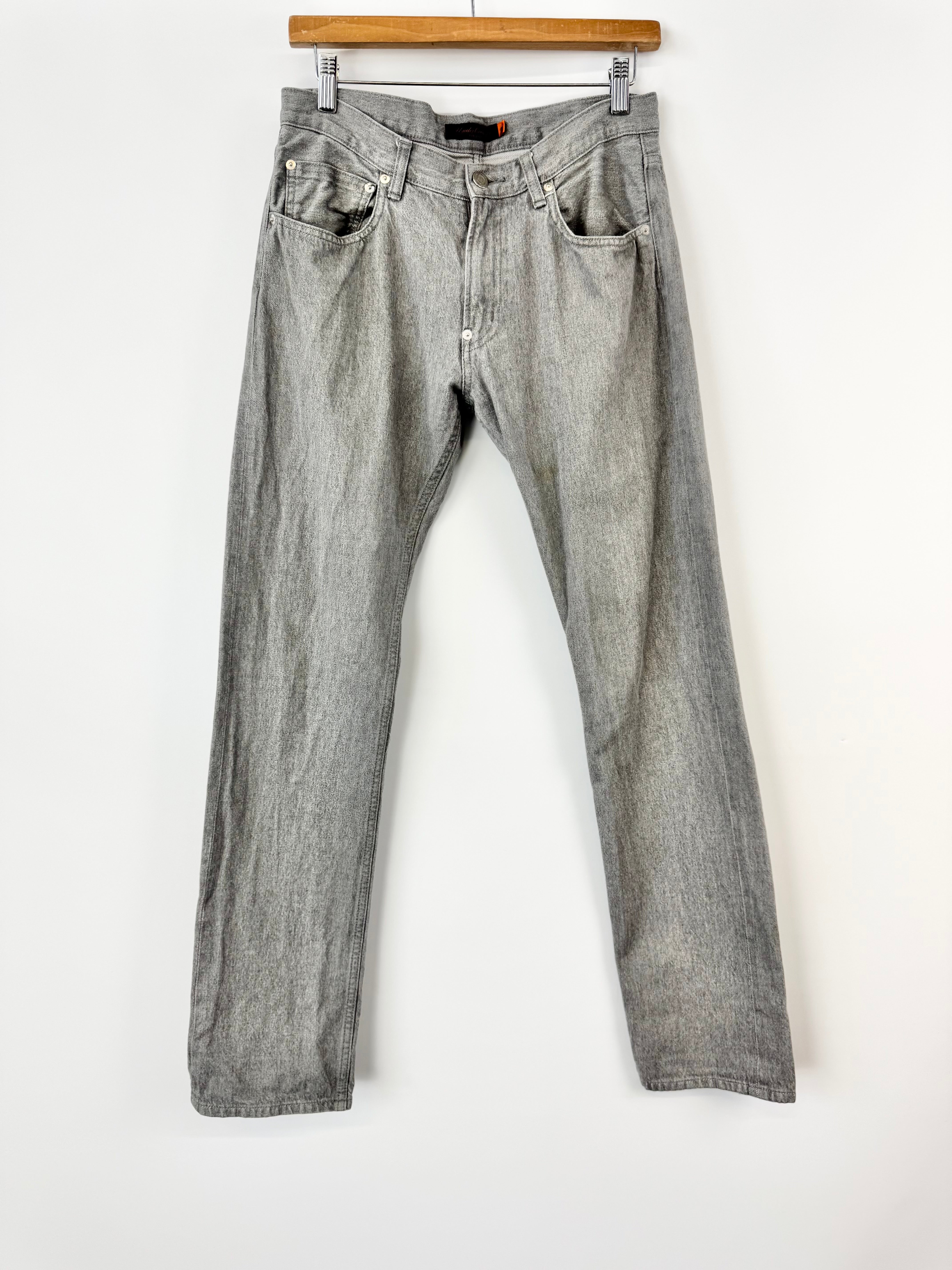 Gray jeans hanging on a wooden hanger against a white background