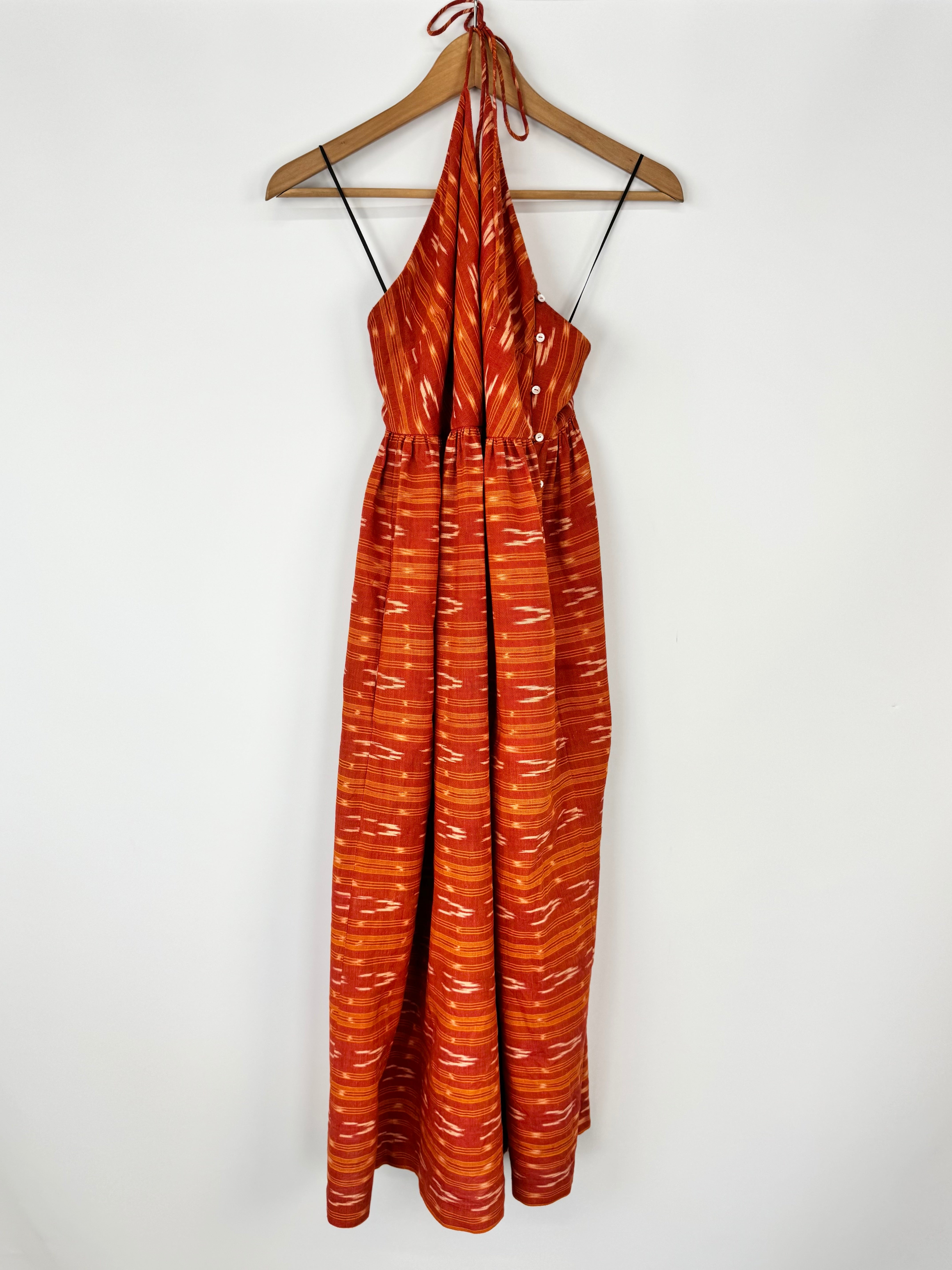Orange patterned dress on a hanger against a white background