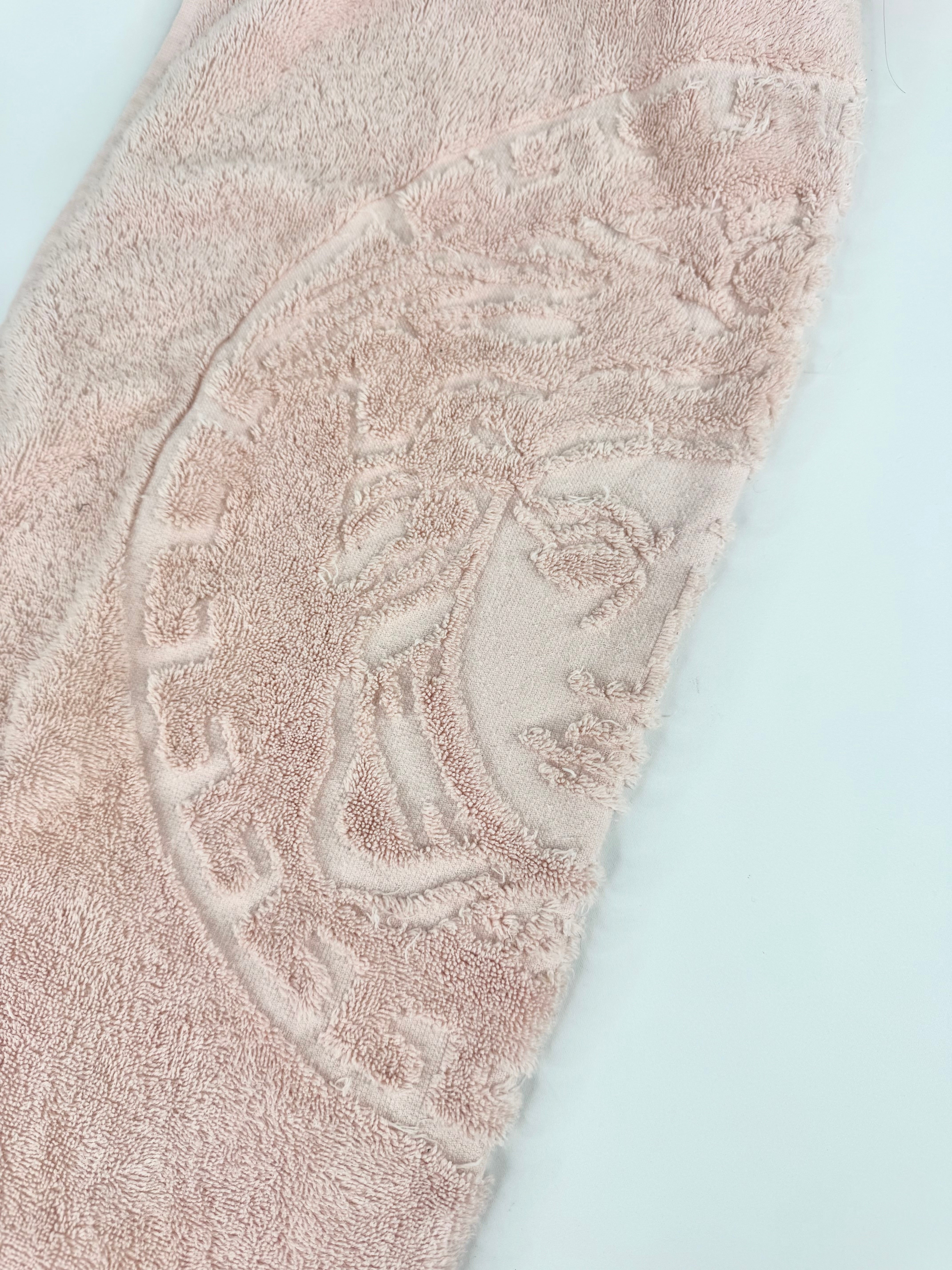Close-up of a textured beige towel with a circular pattern on a light blue background