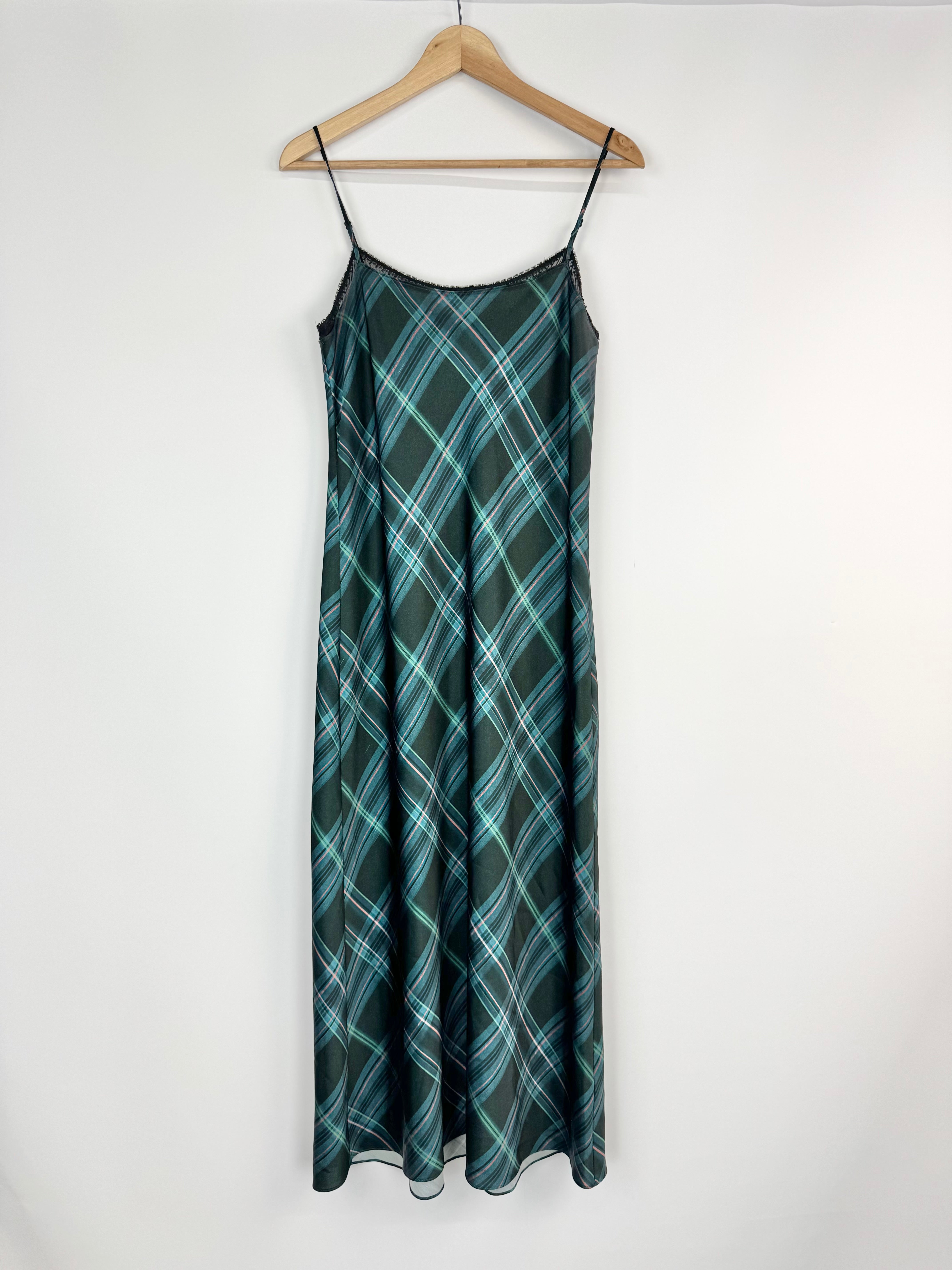 Plaid slip dress on a hanger against a white background