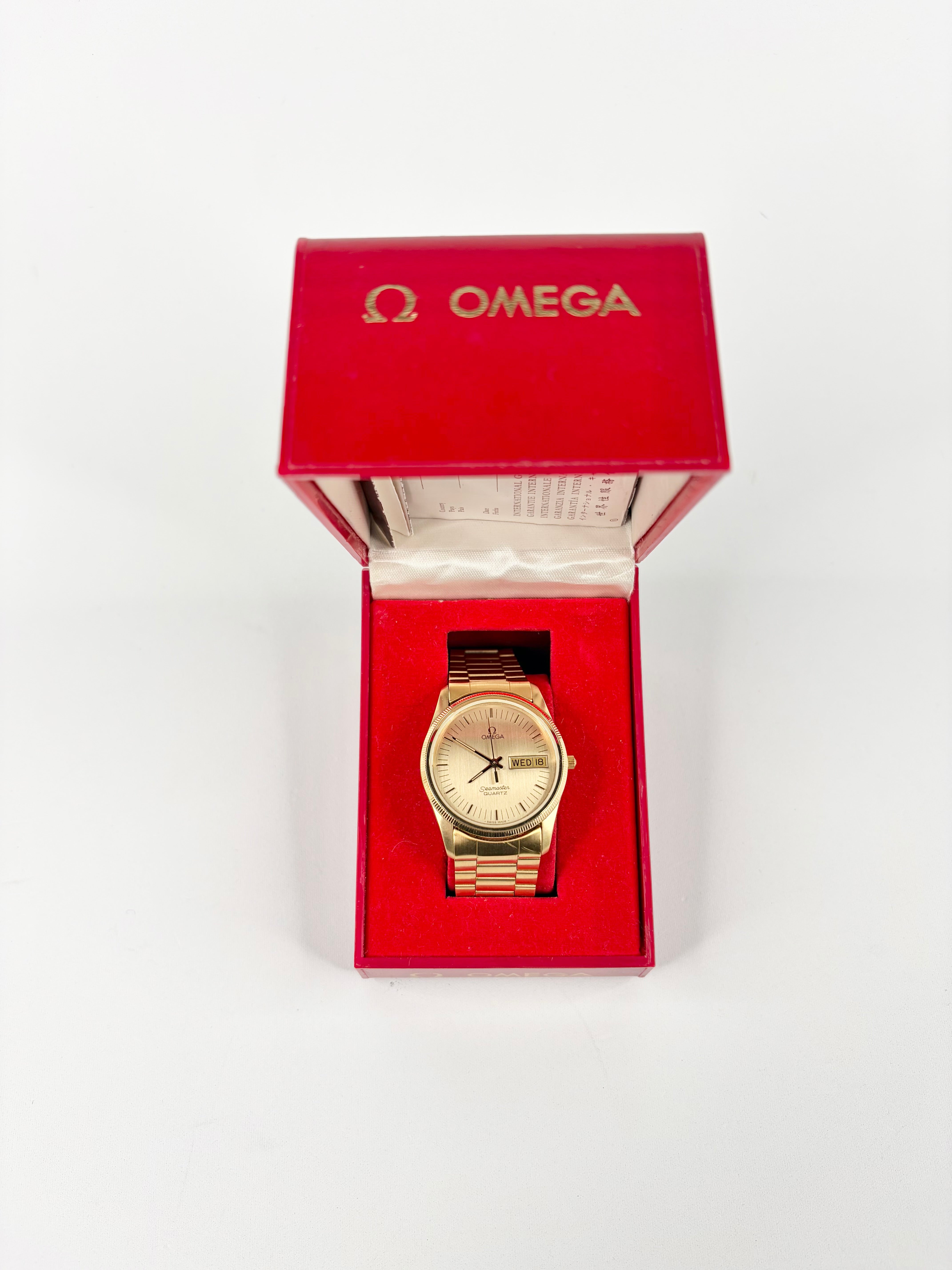 Gold watch in a red Omega box on a white background
