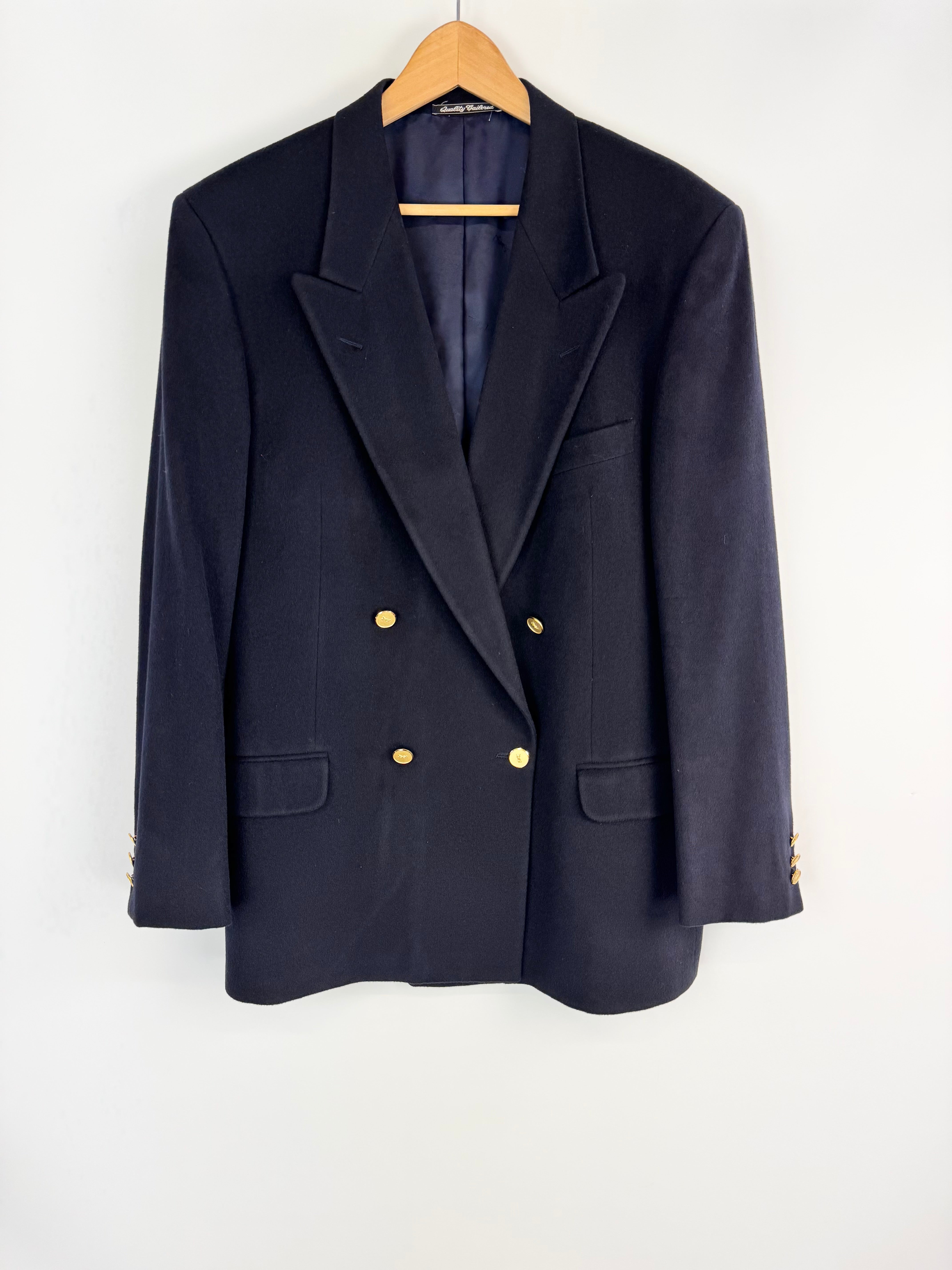 Navy blazer with gold buttons on a hanger against a white background
