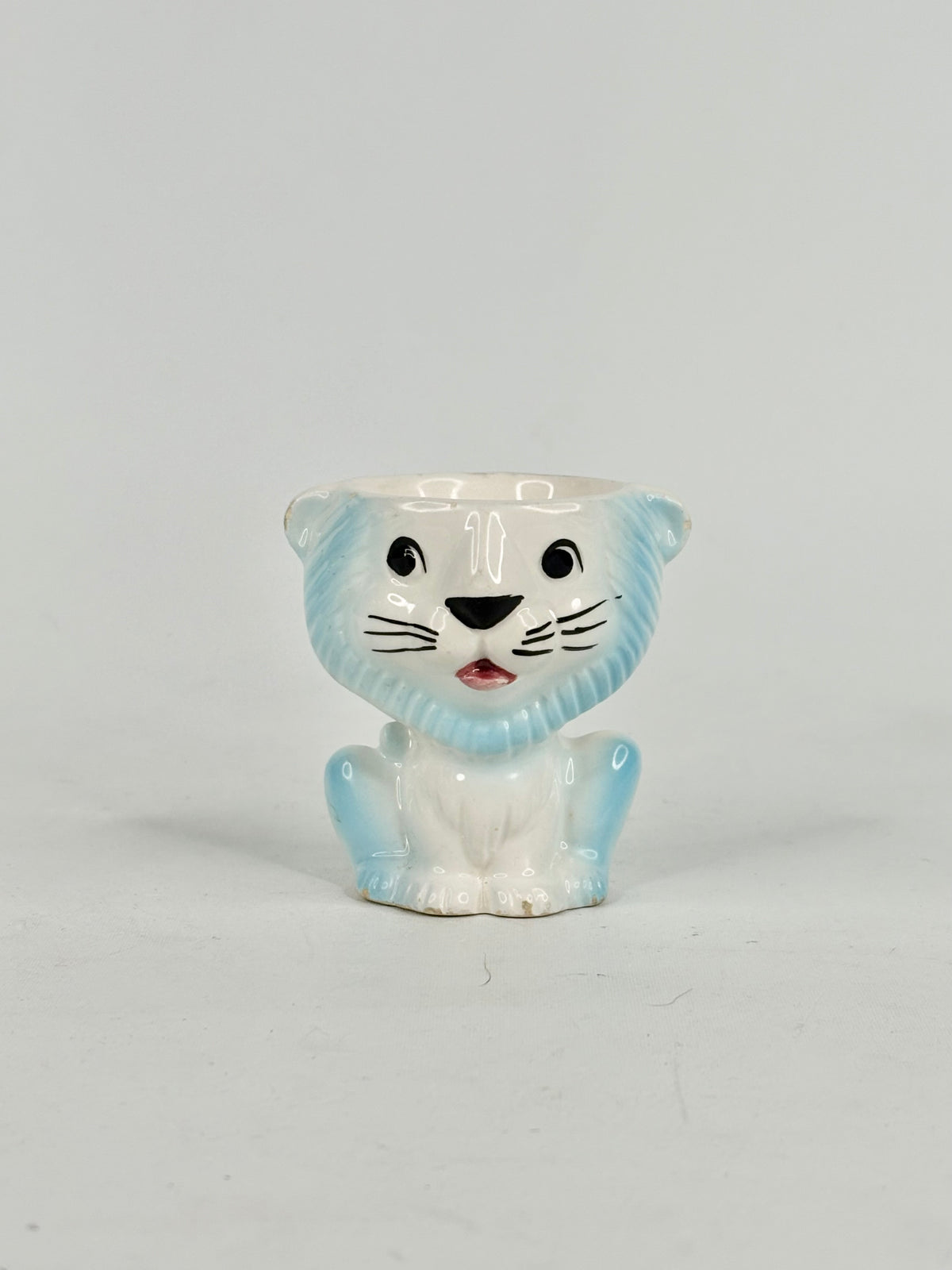 White ceramic tiger planter with blue accents on a light gray background