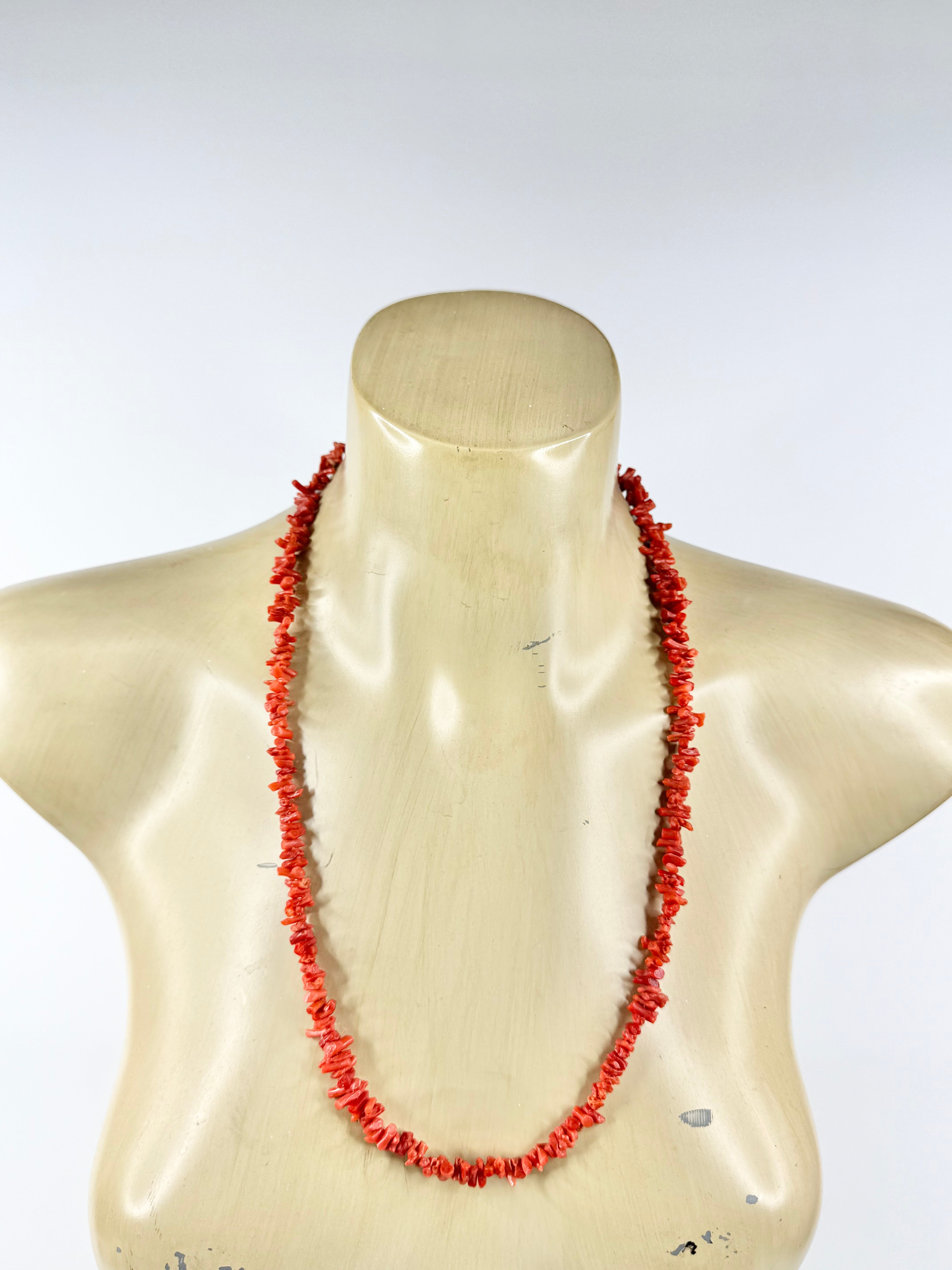 Red coral necklace on a mannequin bust against a white background