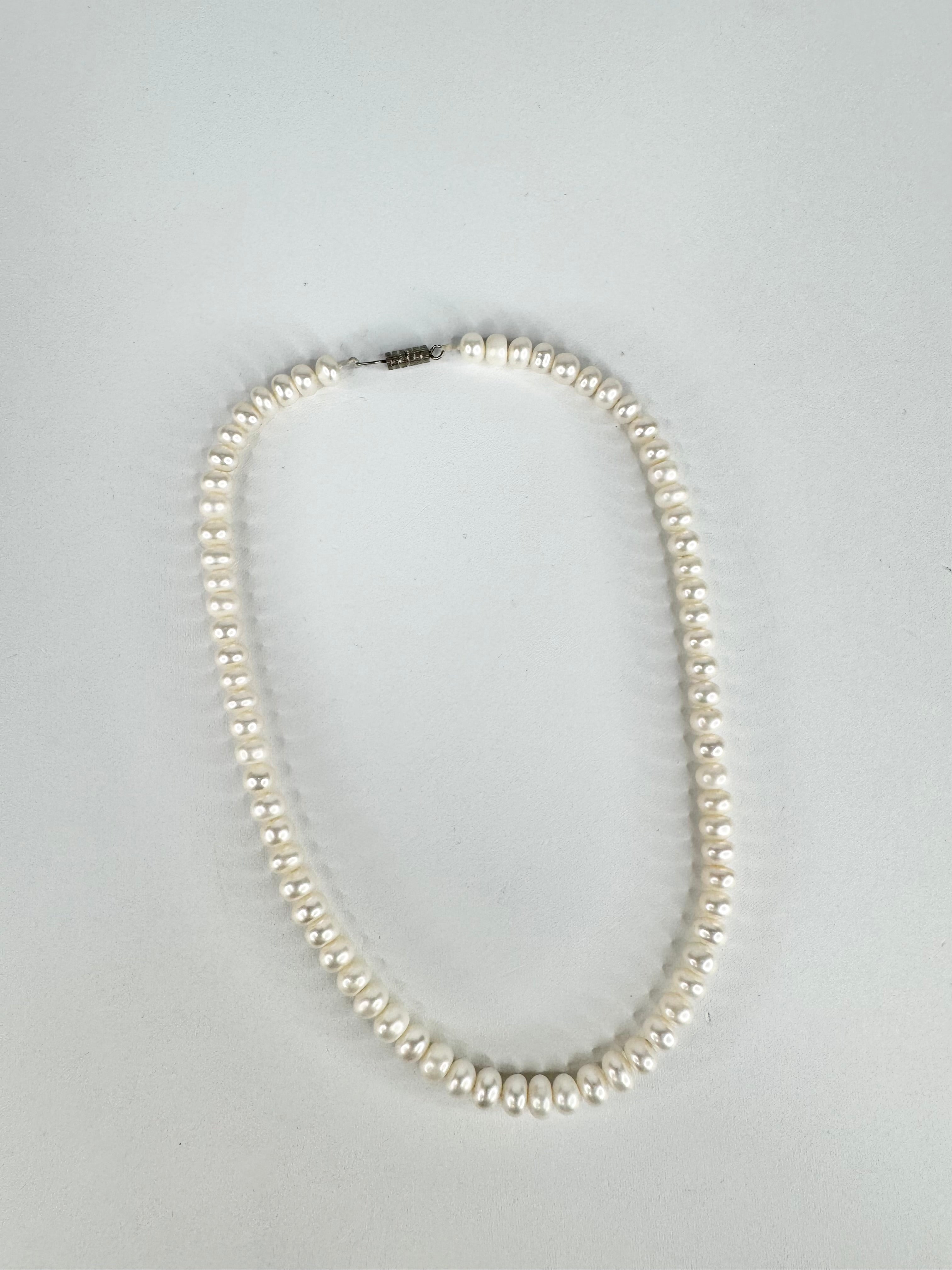 Pearl necklace on a light gray background