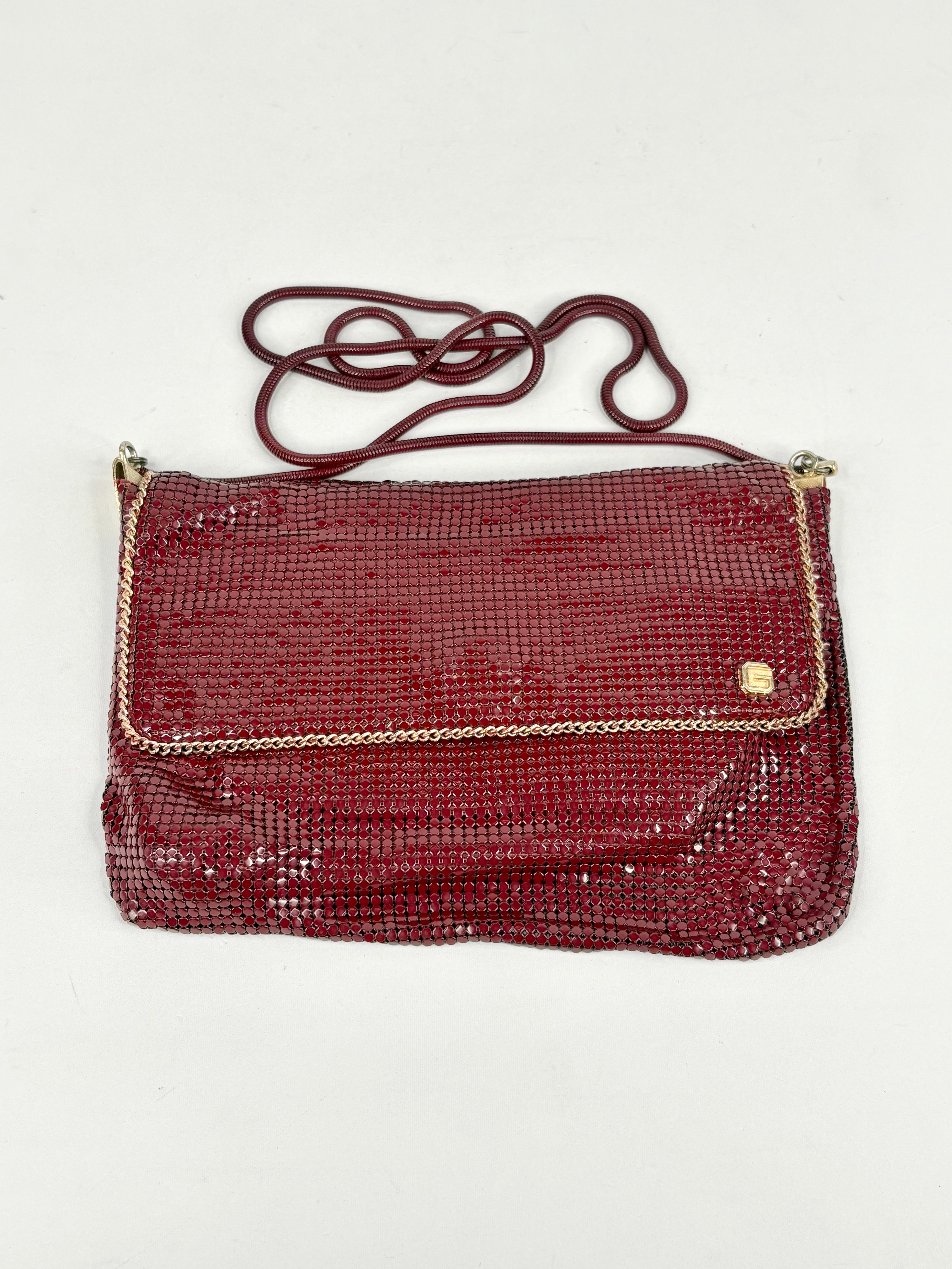 Red textured handbag with gold chain detail on a white background