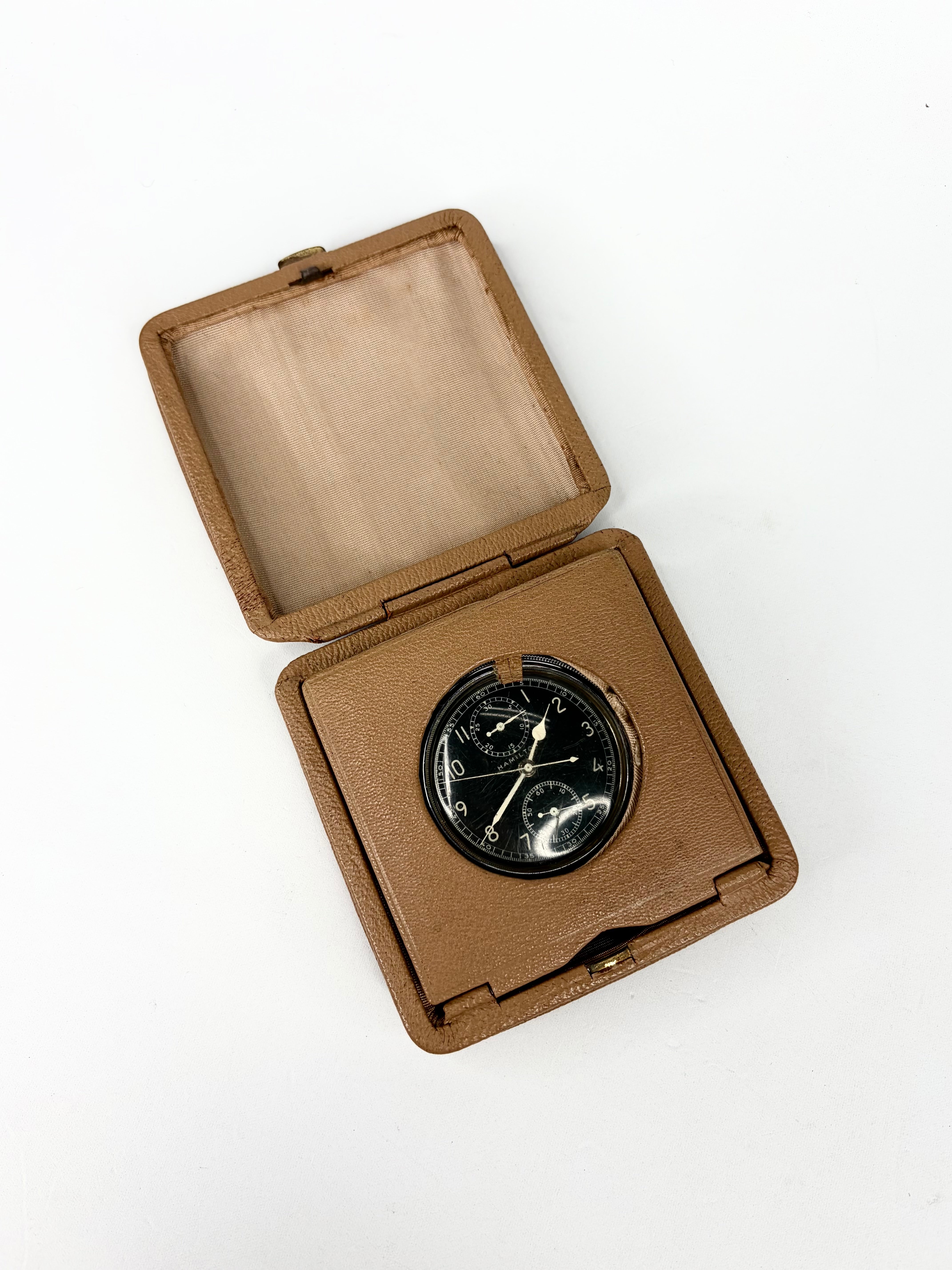 Pocket watch in a brown leather case on a white background