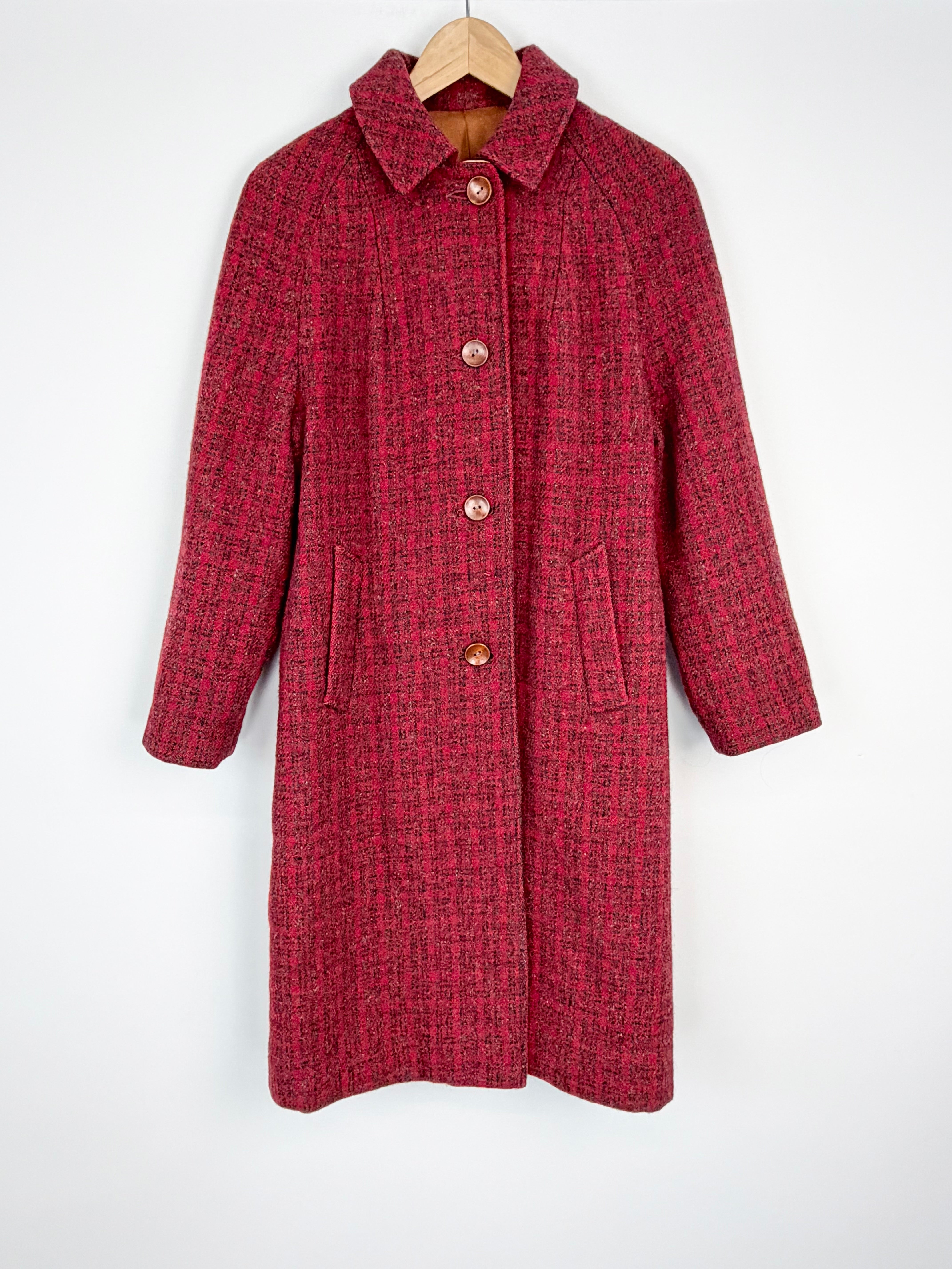 Red textured coat on a hanger against a white background