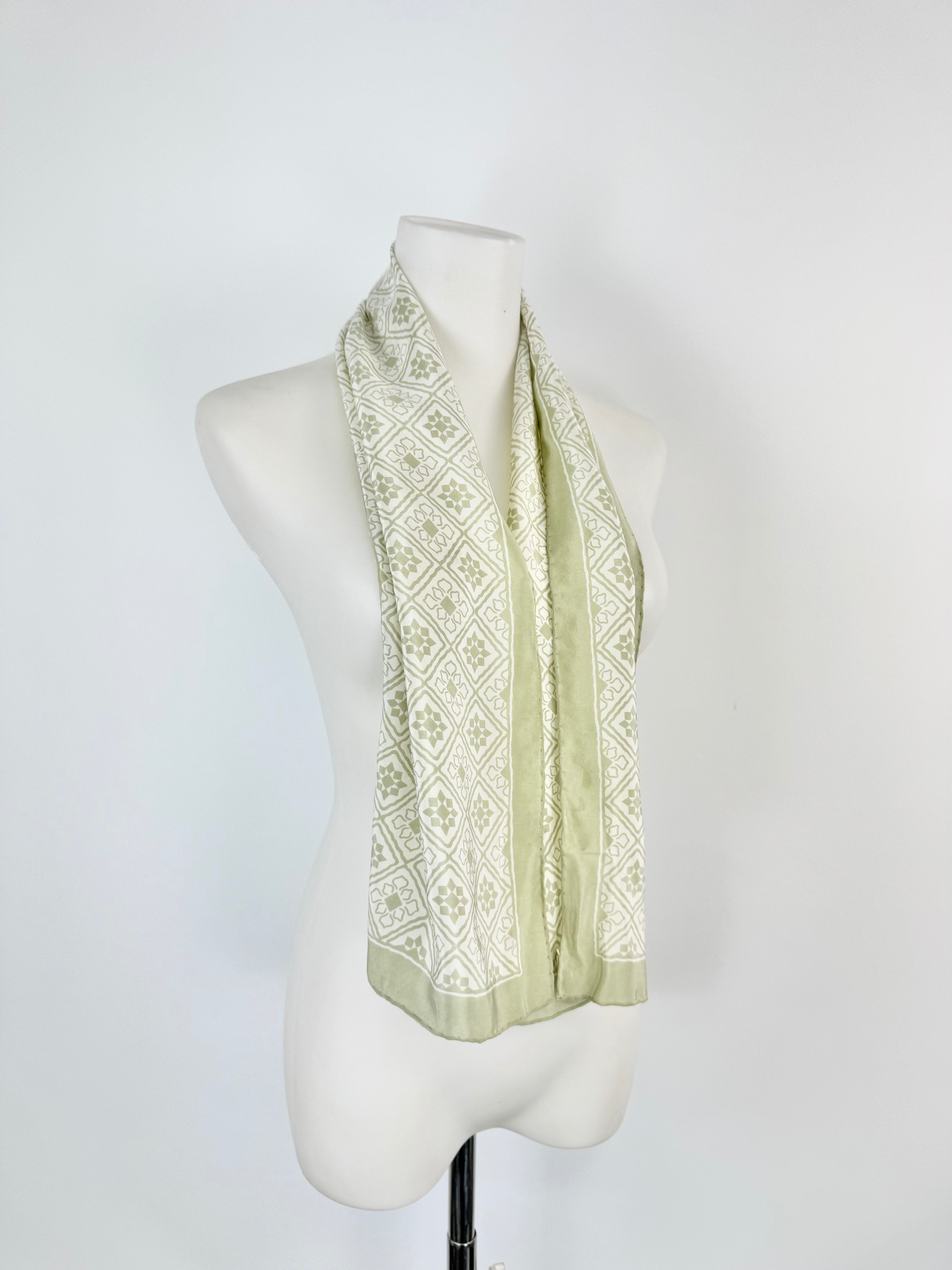 Light green patterned scarf on a mannequin against a white background