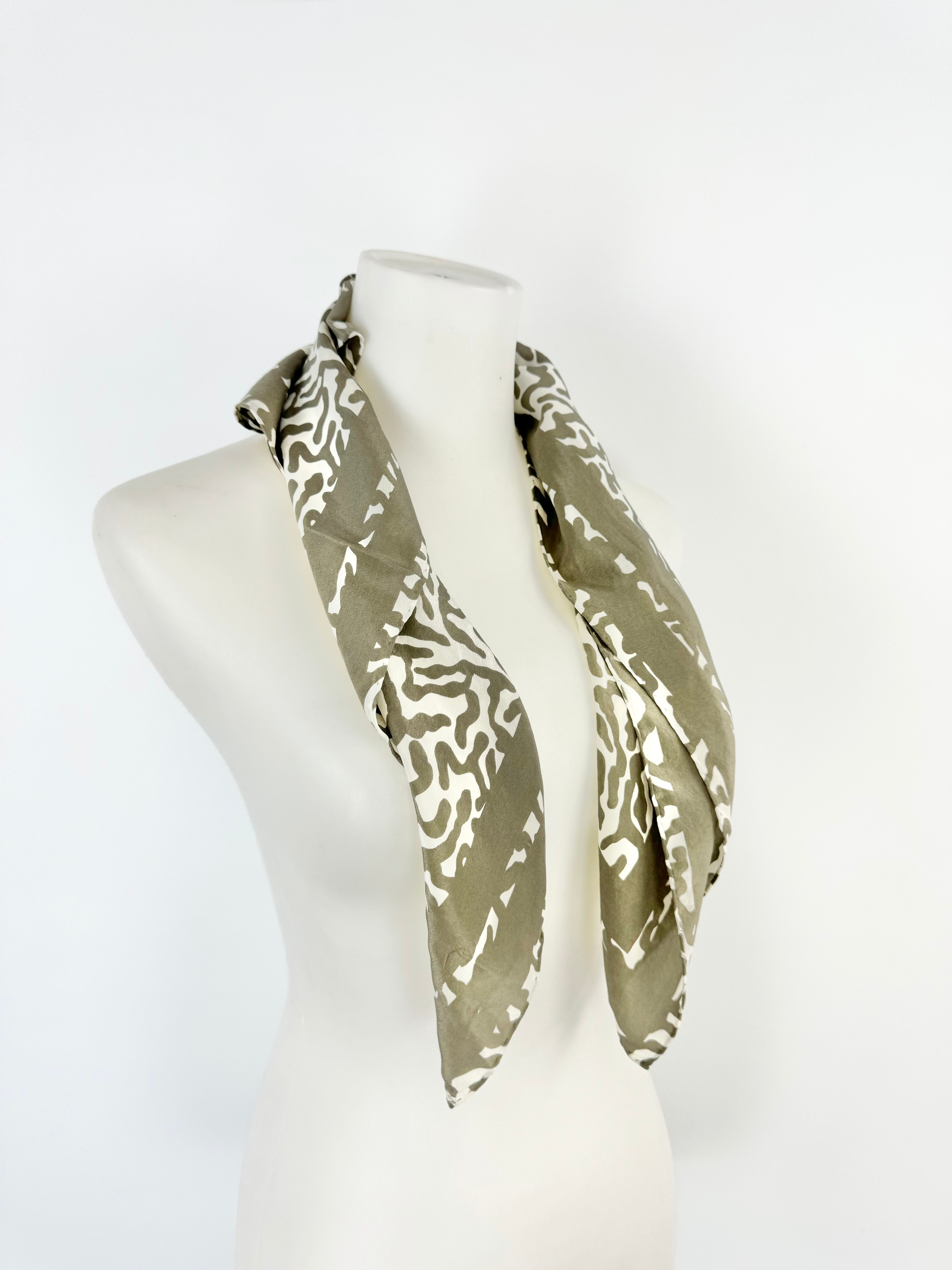 Green and white patterned scarf on a mannequin head against a white background