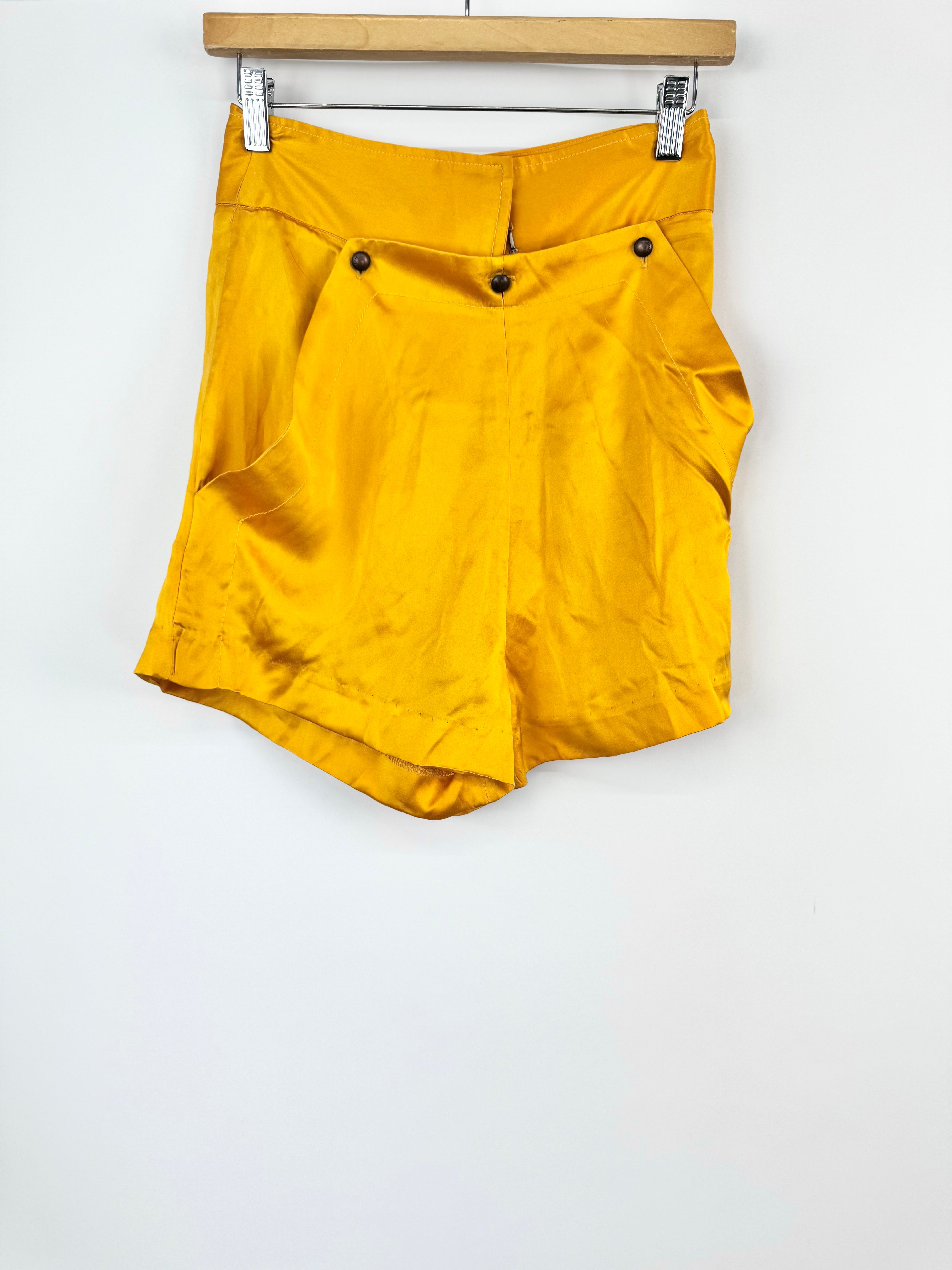 Yellow shorts hanging on a wooden rod against a white background
