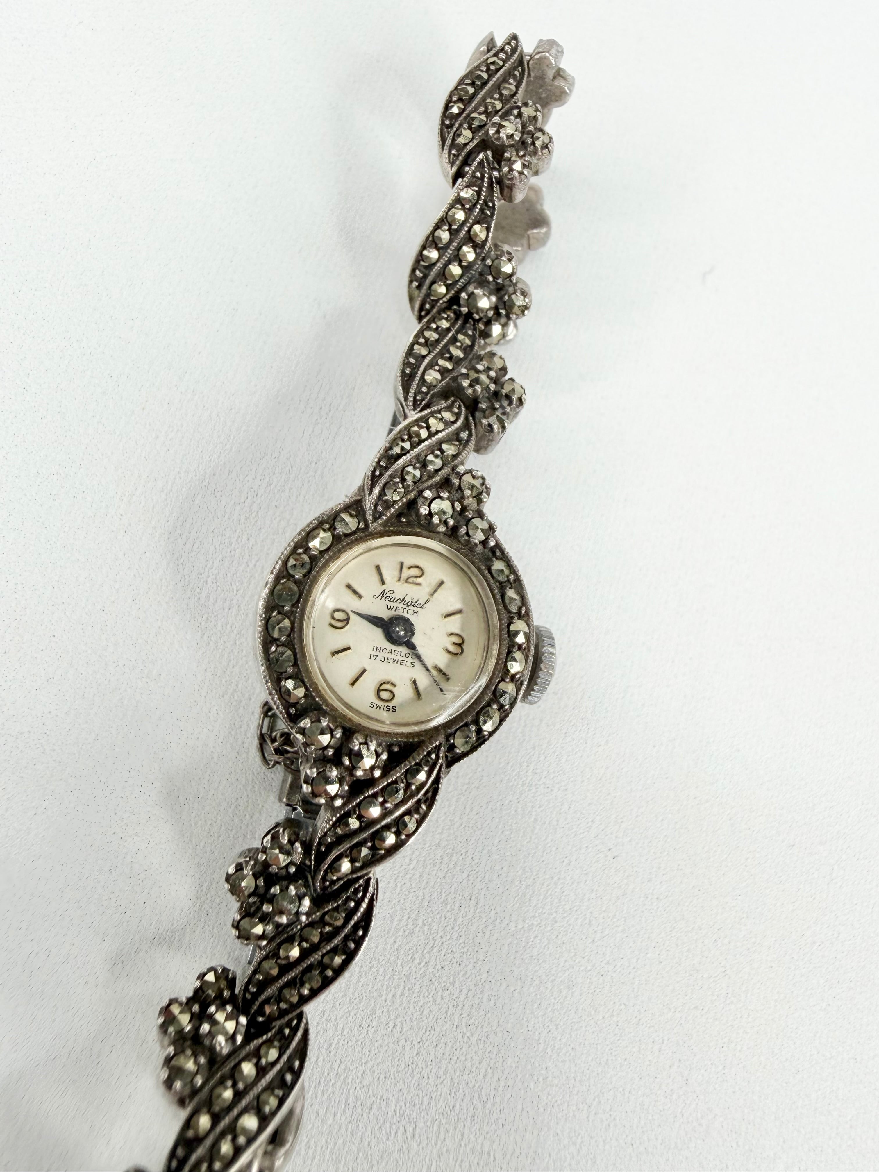 Silver watch with braided design on a white background