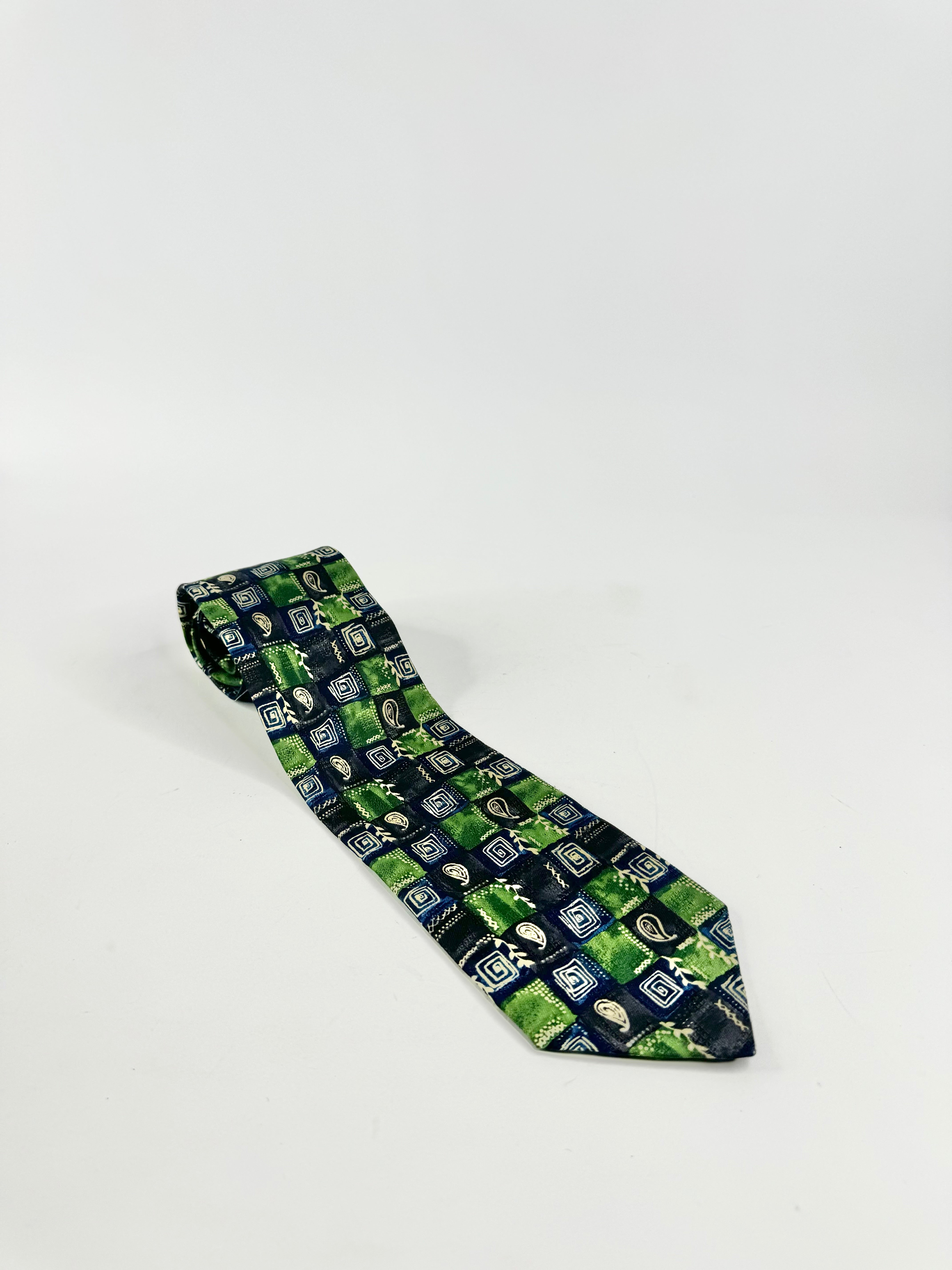 A vintage Pierre Cardin necktie with a green and blue geometric pattern on a white background.
