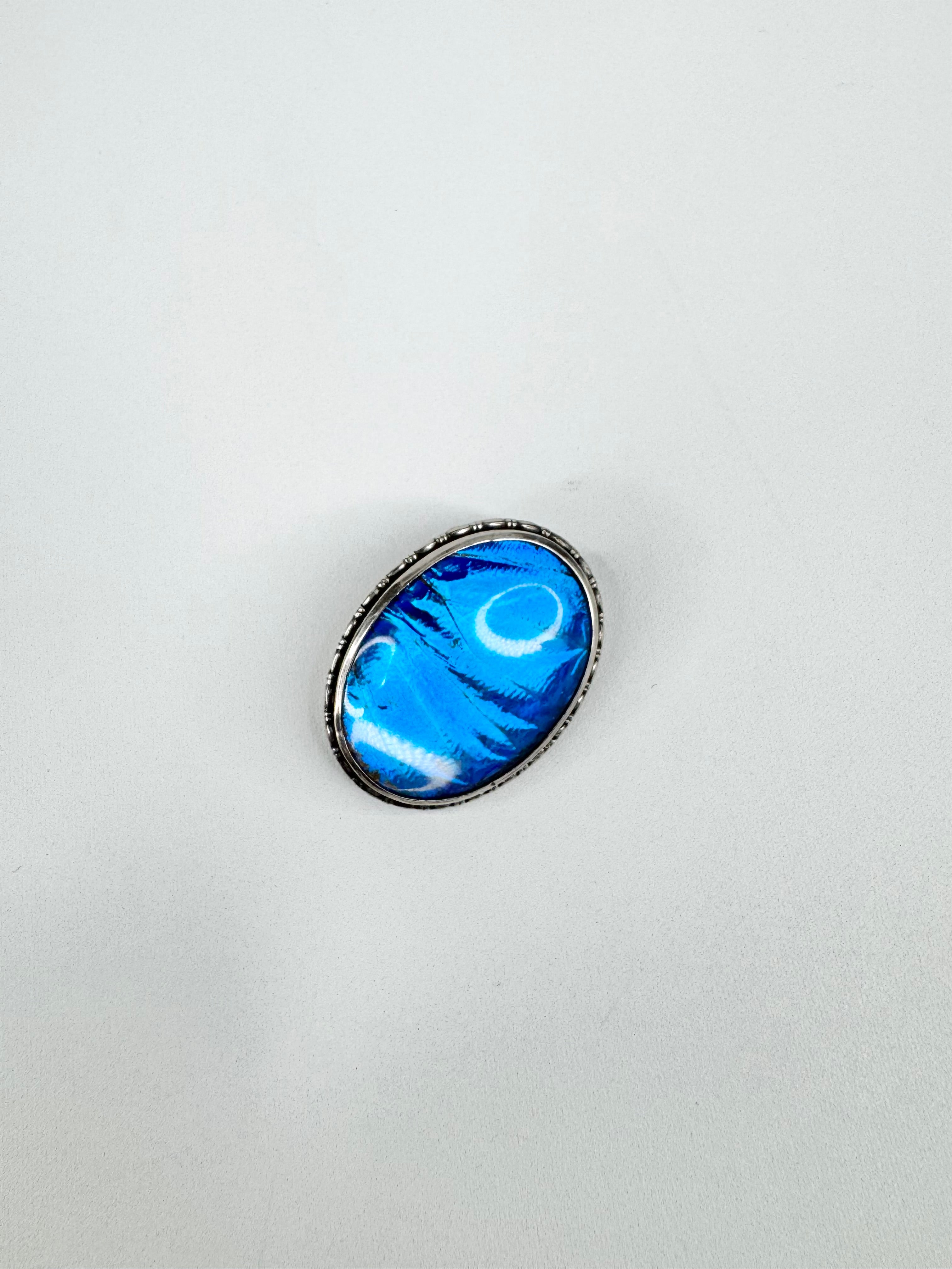 Blue oval stone in a silver frame on a light gray background