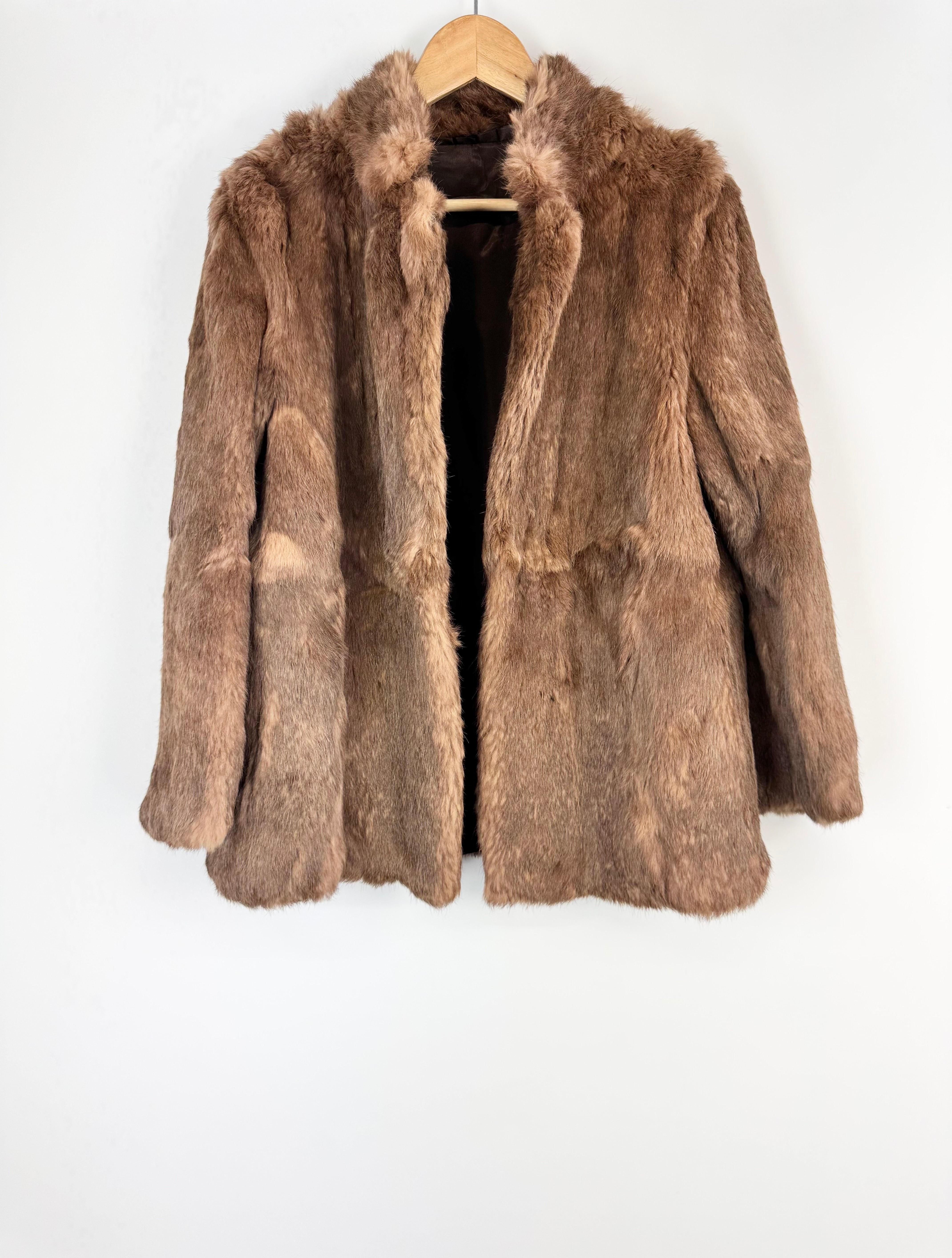 Brown fur coat on a hanger against a white background