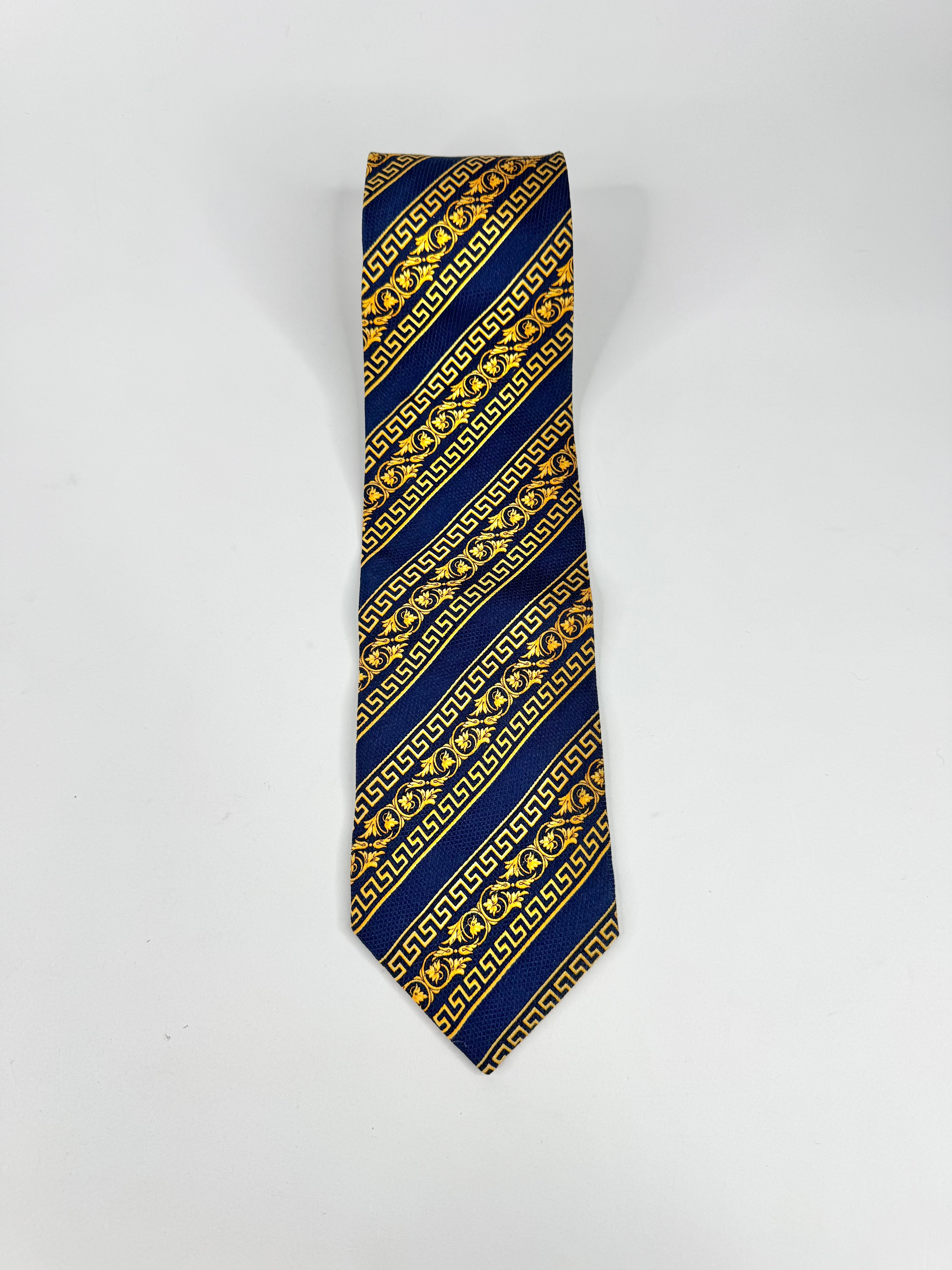 Navy blue tie with gold geometric pattern on a white background