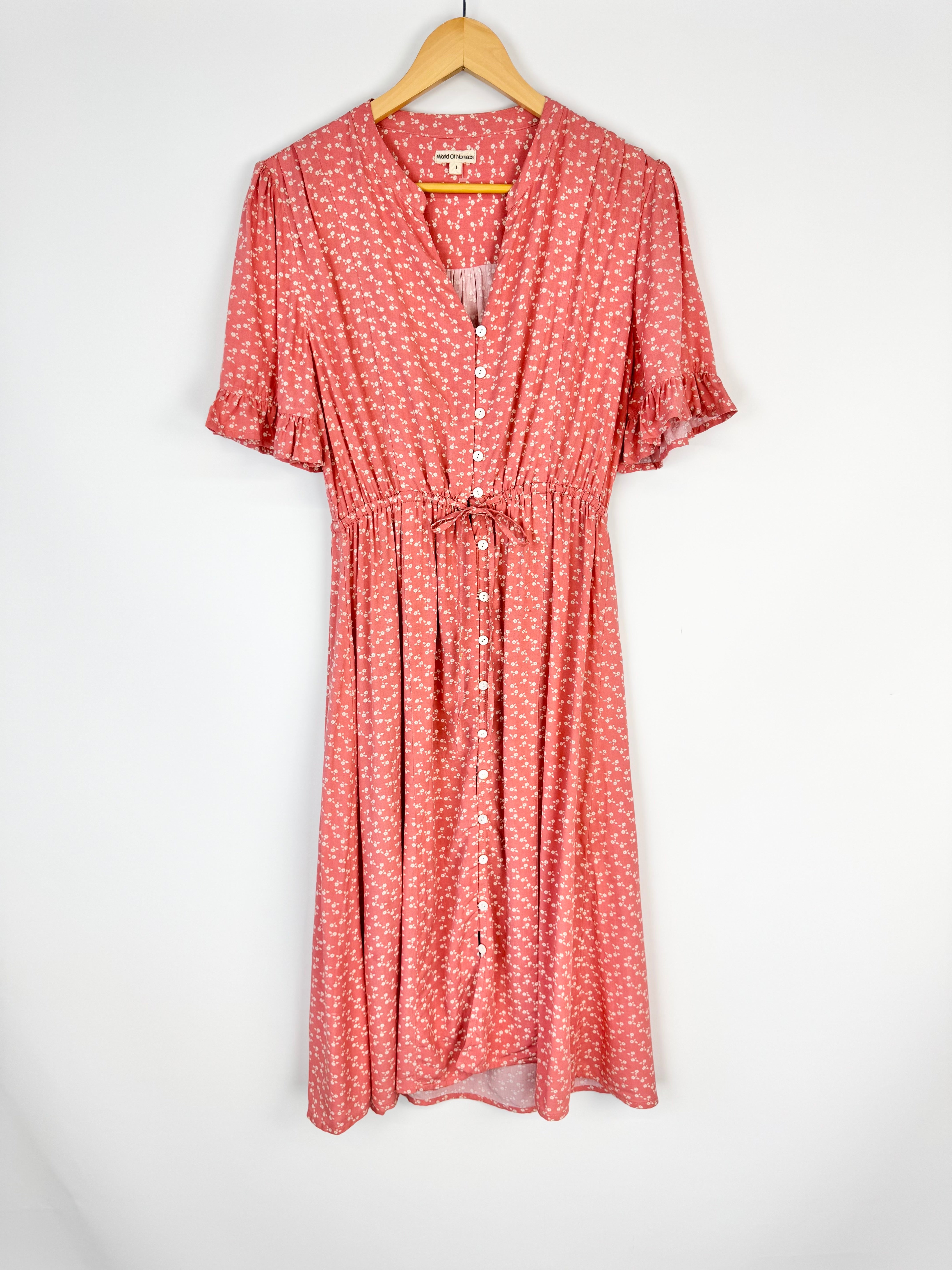 Red floral dress on a hanger against a white background