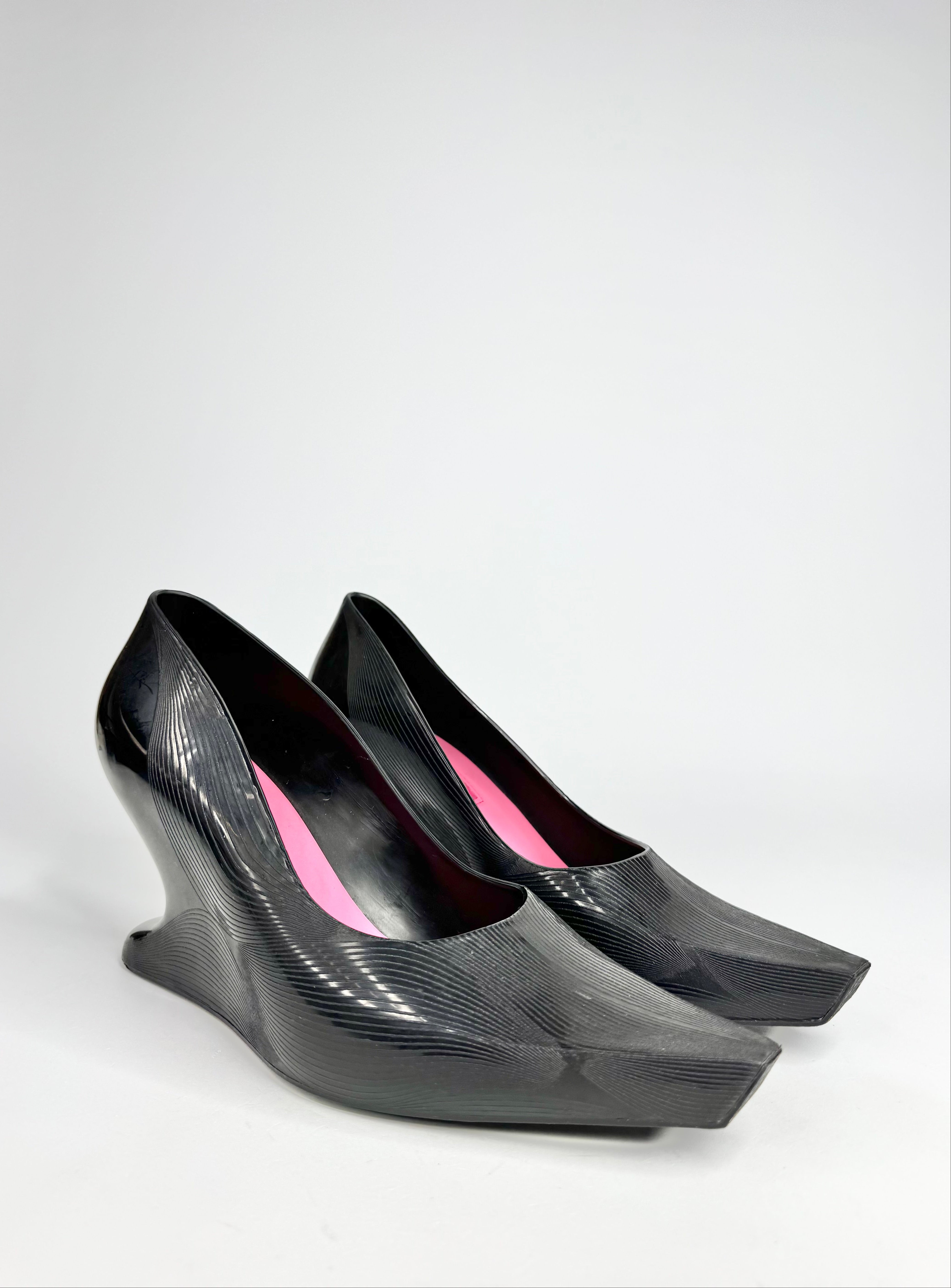 Black high-heeled shoes with pink interior on a white background