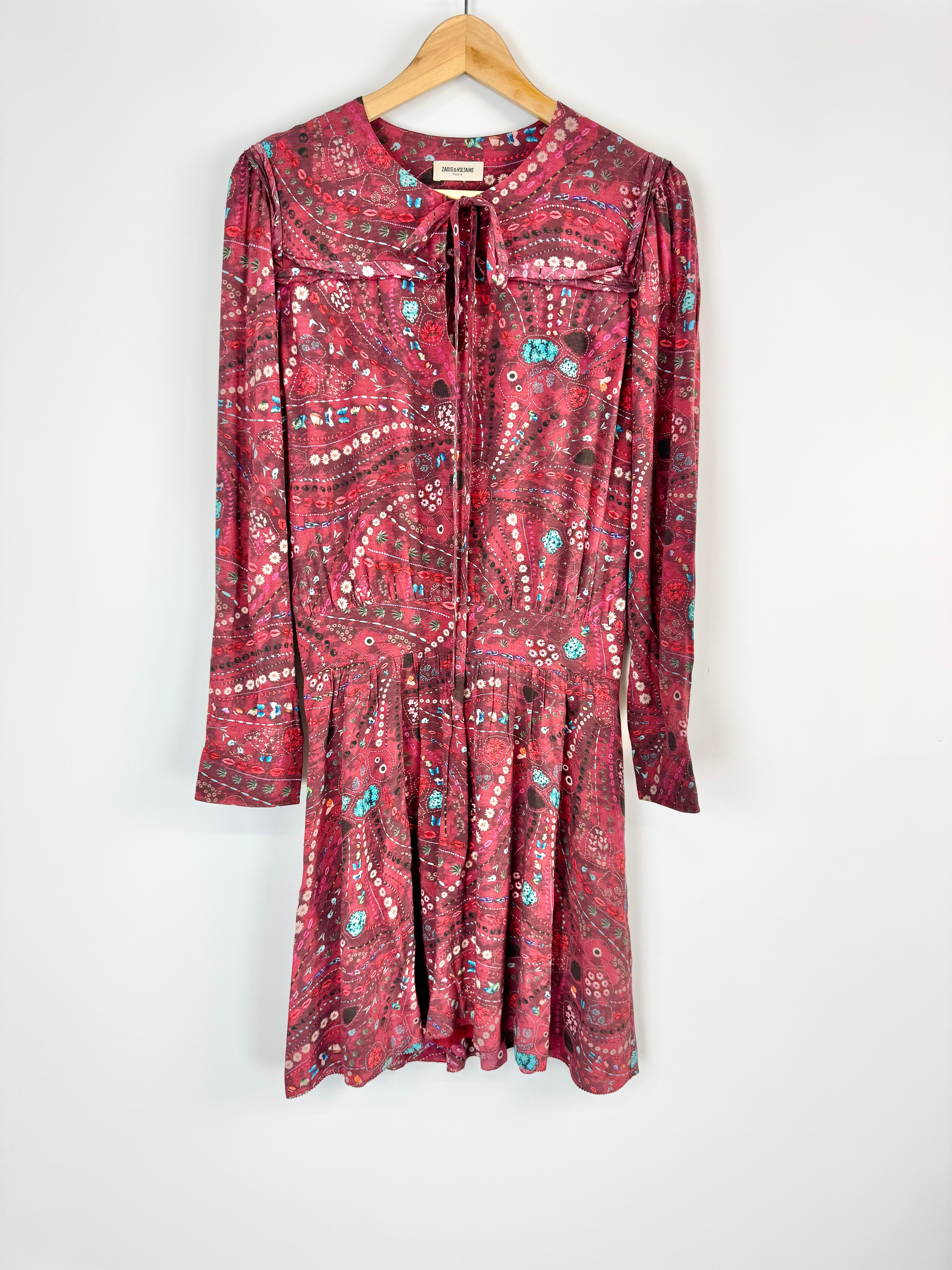 Red patterned dress on a hanger against a white background