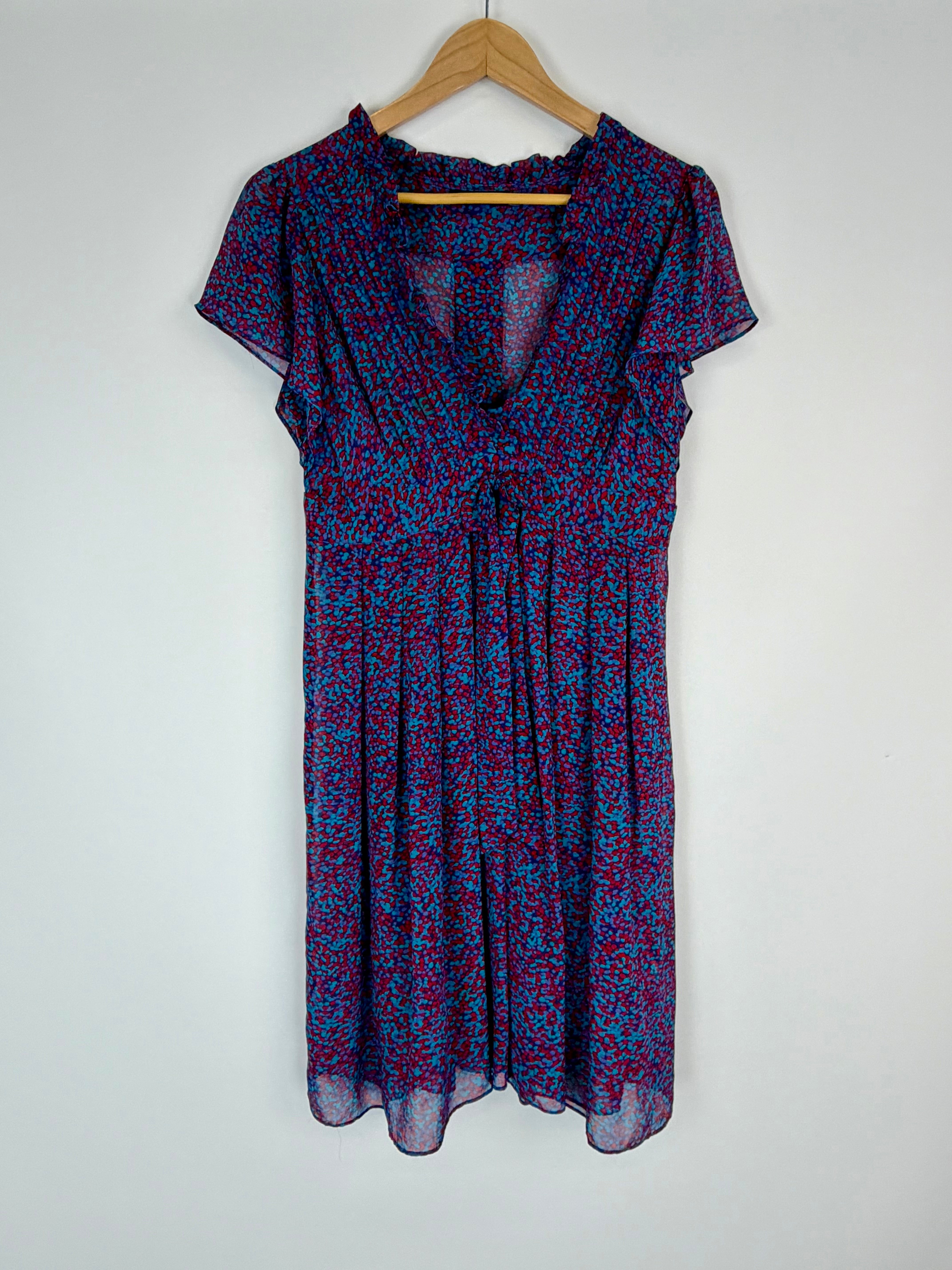 Blue and red patterned dress on a wooden hanger against a white background