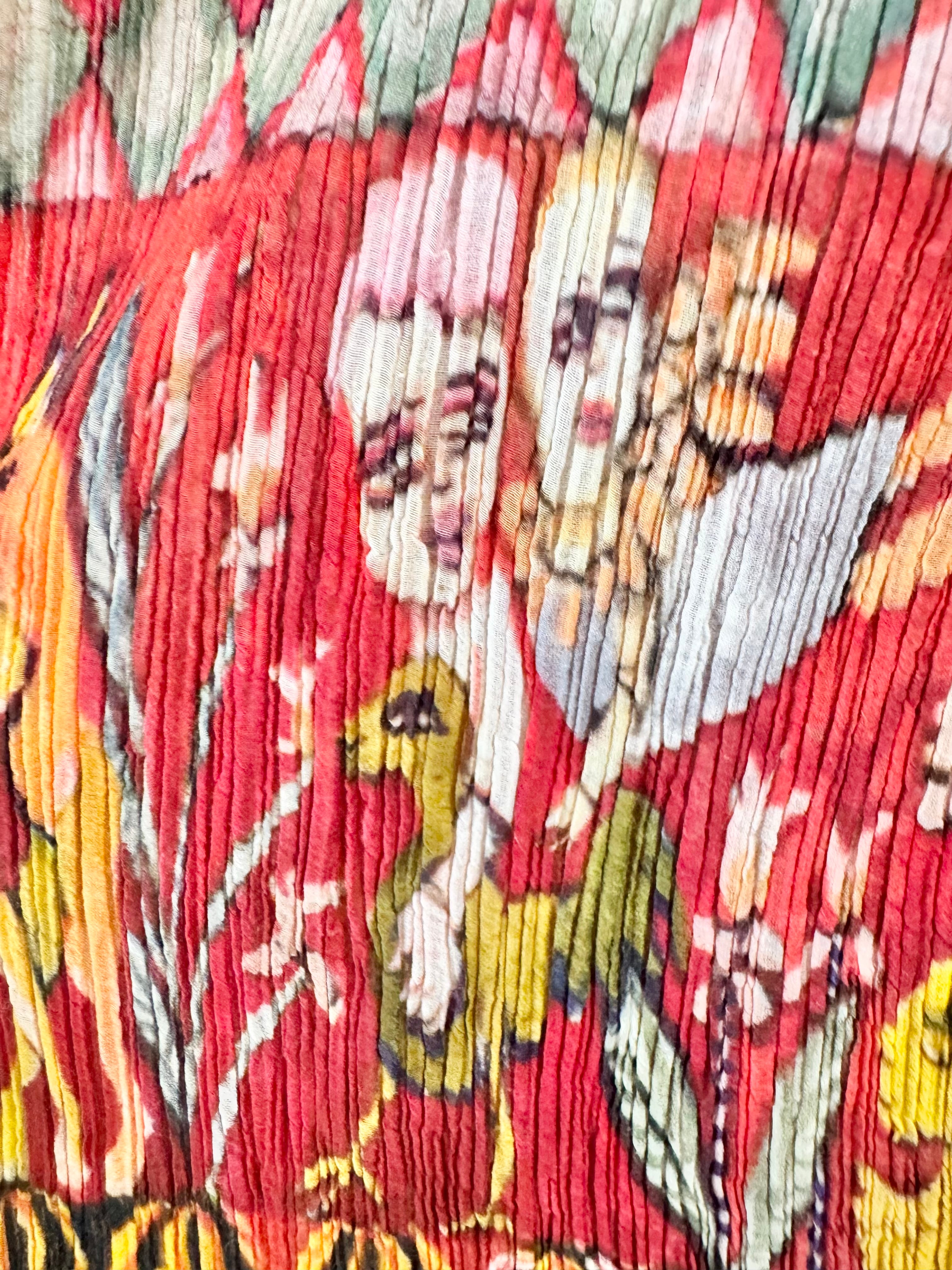 Close-up of a colorful fabric with floral and bird patterns on a red background