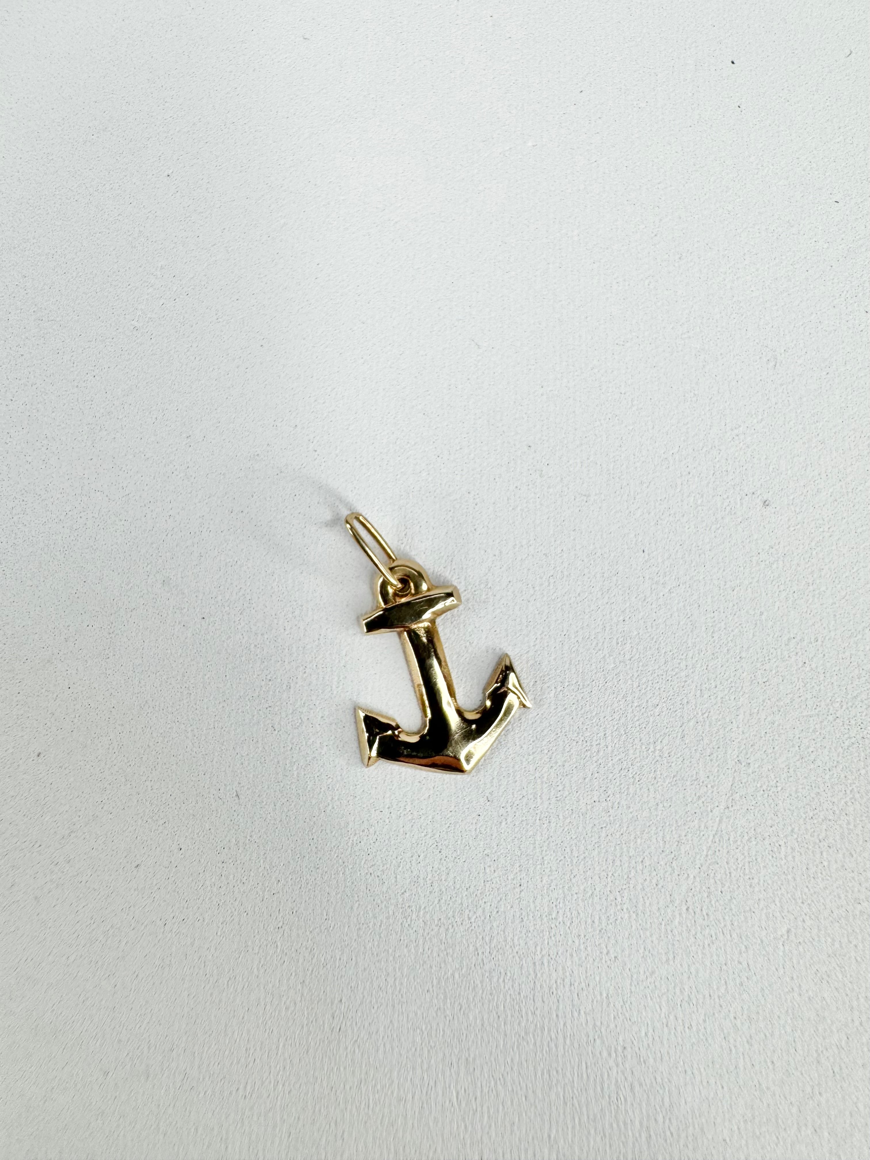 Gold anchor pendant on a white background