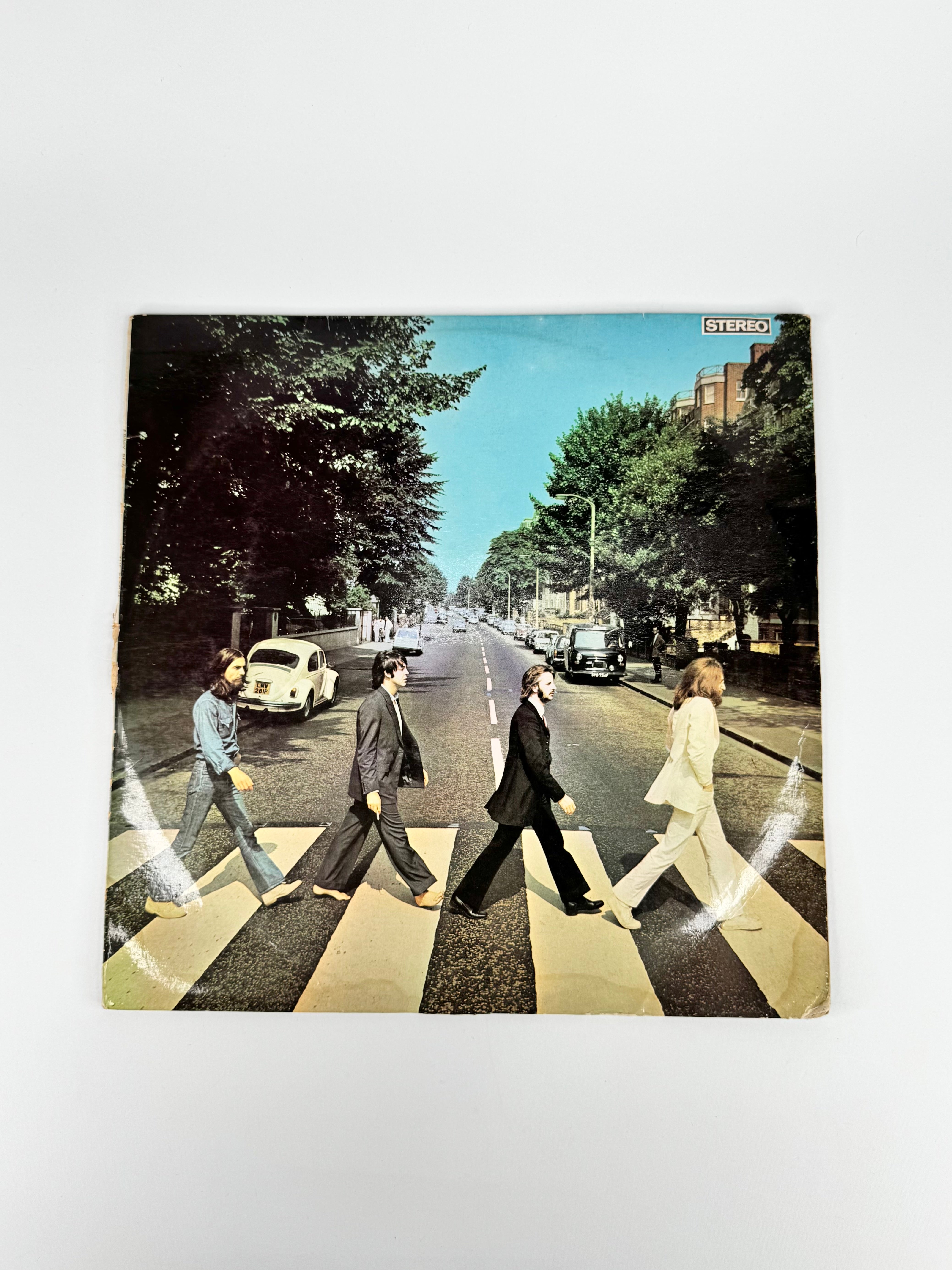 Vinyl record cover with a classic album design featuring four people crossing a zebra crossing.